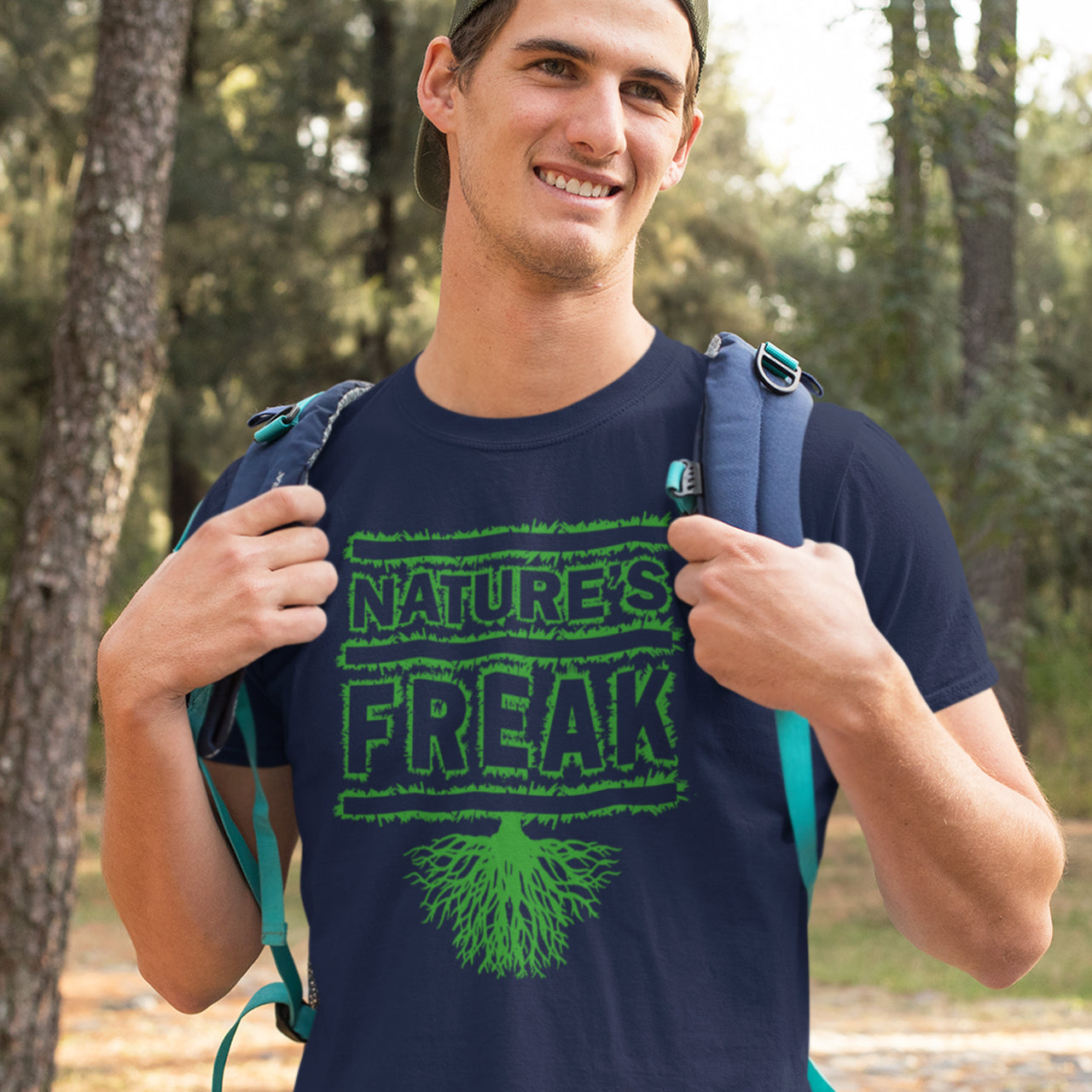Man wearing a French navy blue t-shirt with 'Nature's Freak' design outdoors. A protect the planet t shirt design for all children of nature who are proud to be part of a beautiful eco system. This stencil graffiti t shirt is ideal if you believe you are surrounded by freaks of nature while feeling like one of nature's freaks. Made from 100% organic ring-spun cotton, this nature lover t shirt is unisex, high-quality, super comfy, and best of all, eco-friendly.
