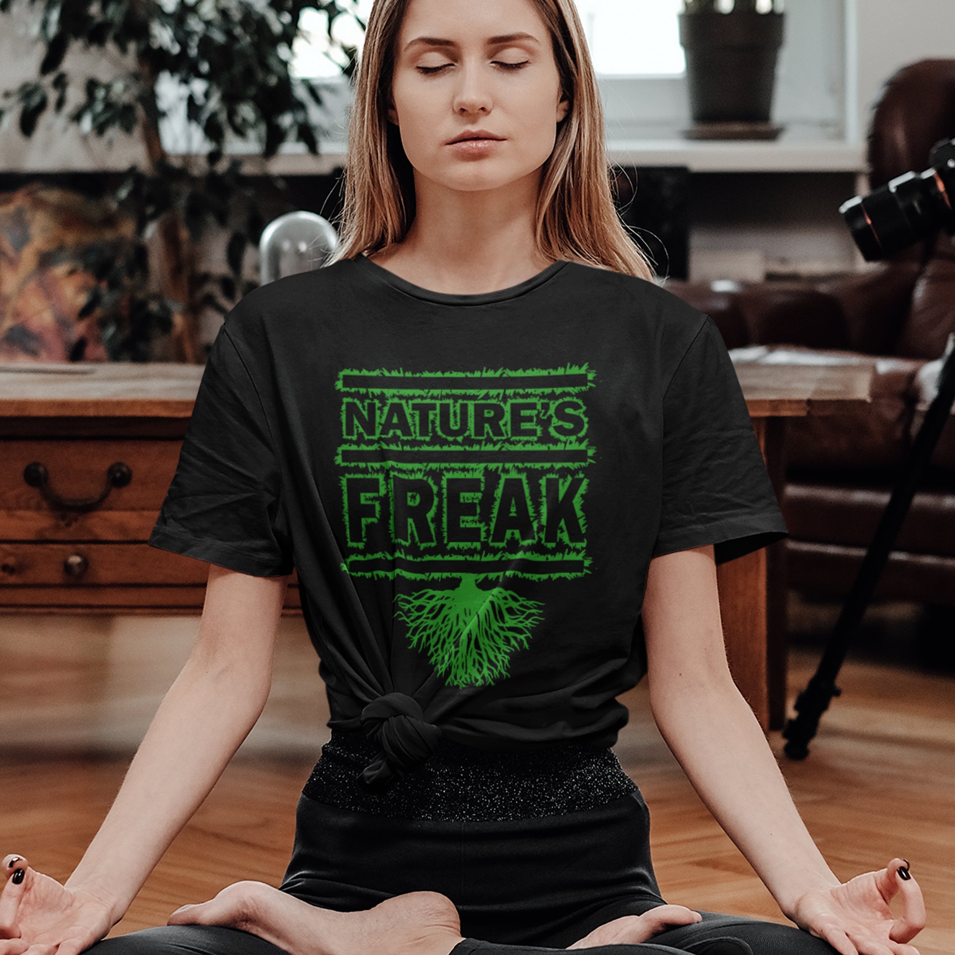 Woman meditating wearing a black t-shirt with 'Nature's Freak' design. A protect the planet t shirt design for all children of nature who are proud to be part of a beautiful eco system. This stencil graffiti t shirt is ideal if you believe you are surrounded by freaks of nature while feeling like one of nature's freaks. Made from 100% organic ring-spun cotton, this nature lover t shirt is unisex, high-quality, super comfy, and best of all, eco-friendly.