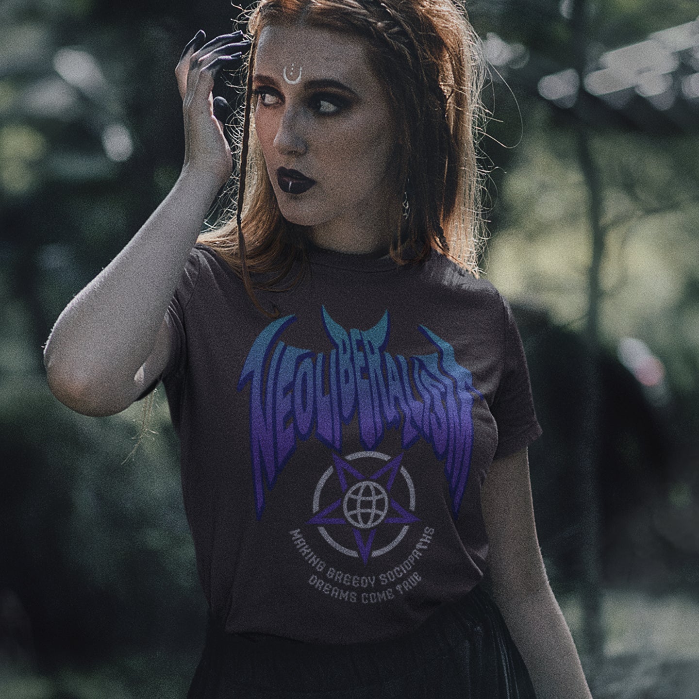 Gothic woman wearing a 'neoliberalism' t shirt. An anti capitalism t shirt in a satanic rock band style. This design pays satirical homage to the most overlooked treat to a CIVILISED society. Neoliberalism, the fertile breeding ground for greed and corruption. Made from 100% organic ring-spun cotton, this counter culture t shirt is unisex, high quality, super comfy, and best of all, eco-friendly.