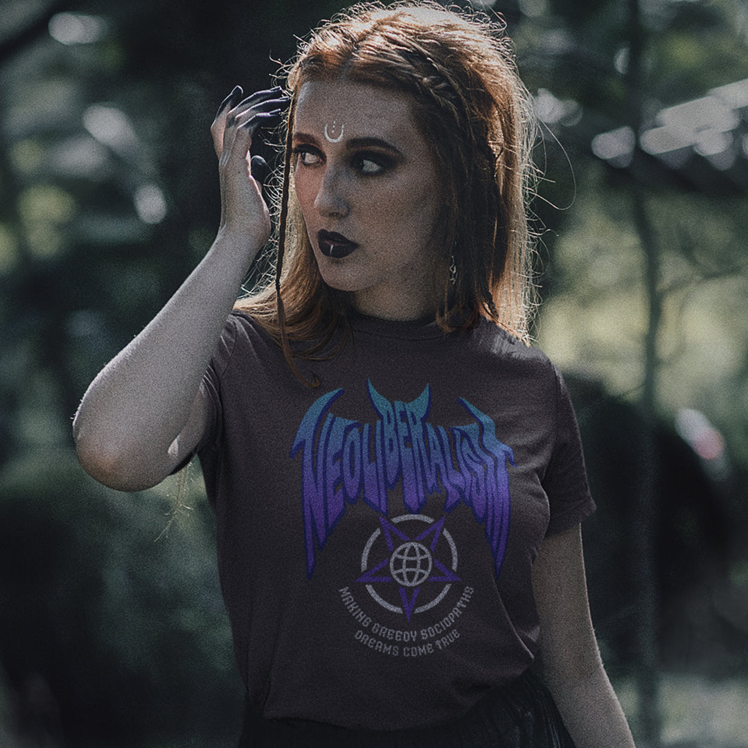 A gothic woman standing outdoors, wearing an anthracite grey t-shirt with "NEOLIBERALISM" logo.