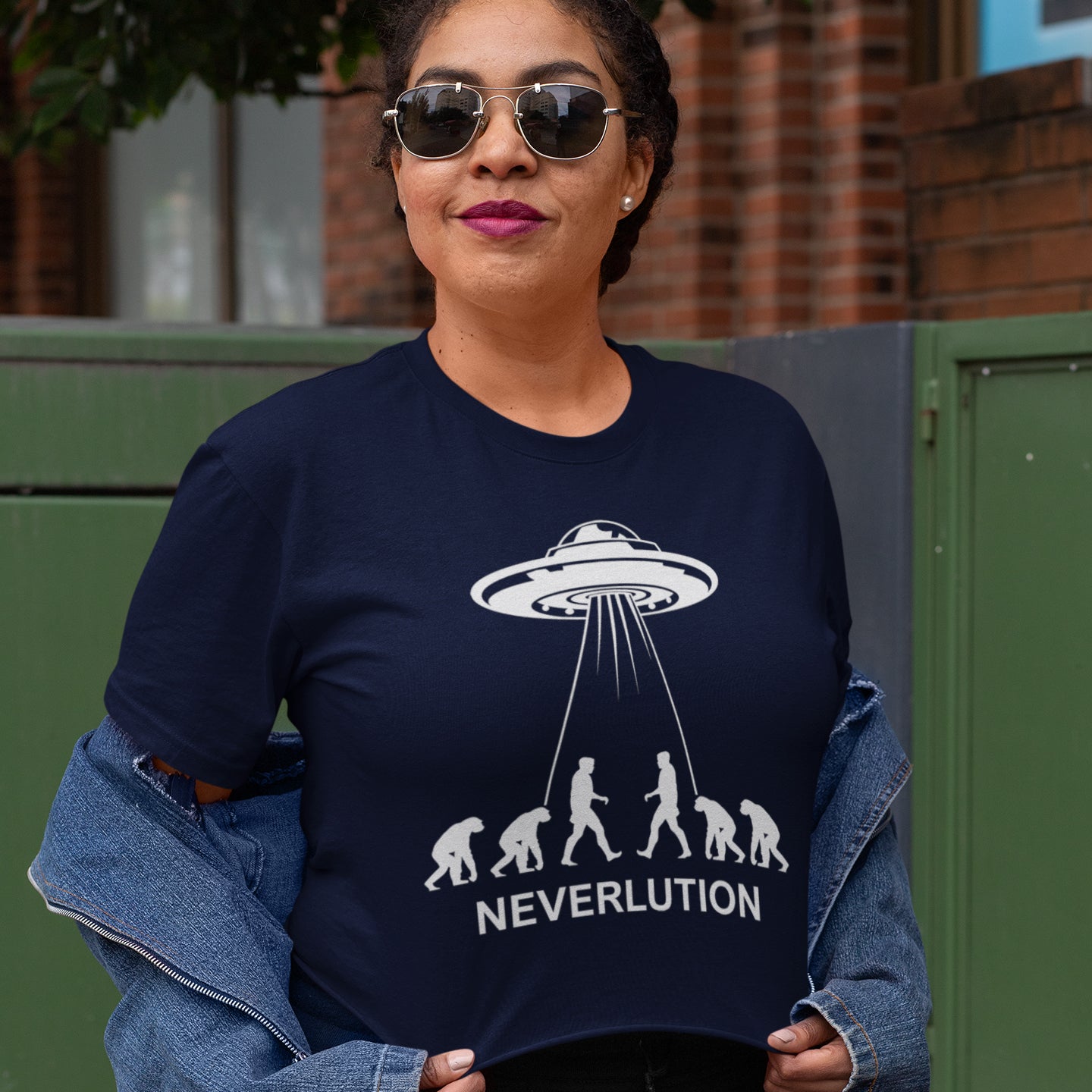 Person wearing a French navy blue sweatshirt with a UFO and evolution graphic, labelled 'NEVERLUTION'. An alien conspiracy theory t-shirt suggesting a different path of our evolution. Did evolution never really happen the way we are told, or is there a more intergalactic and colourful answer ? Made from 100% organic ring-spun cotton, this conspiracy theory t-shirt is unisex, high-quality, super comfy, and best of all, eco-friendly.