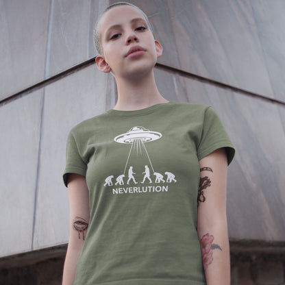 A person wearing an olive green graphic t-shirt with a white UFO and ape evolution design that spells 'NEVERLUTION'. The background is a gray concrete wall.