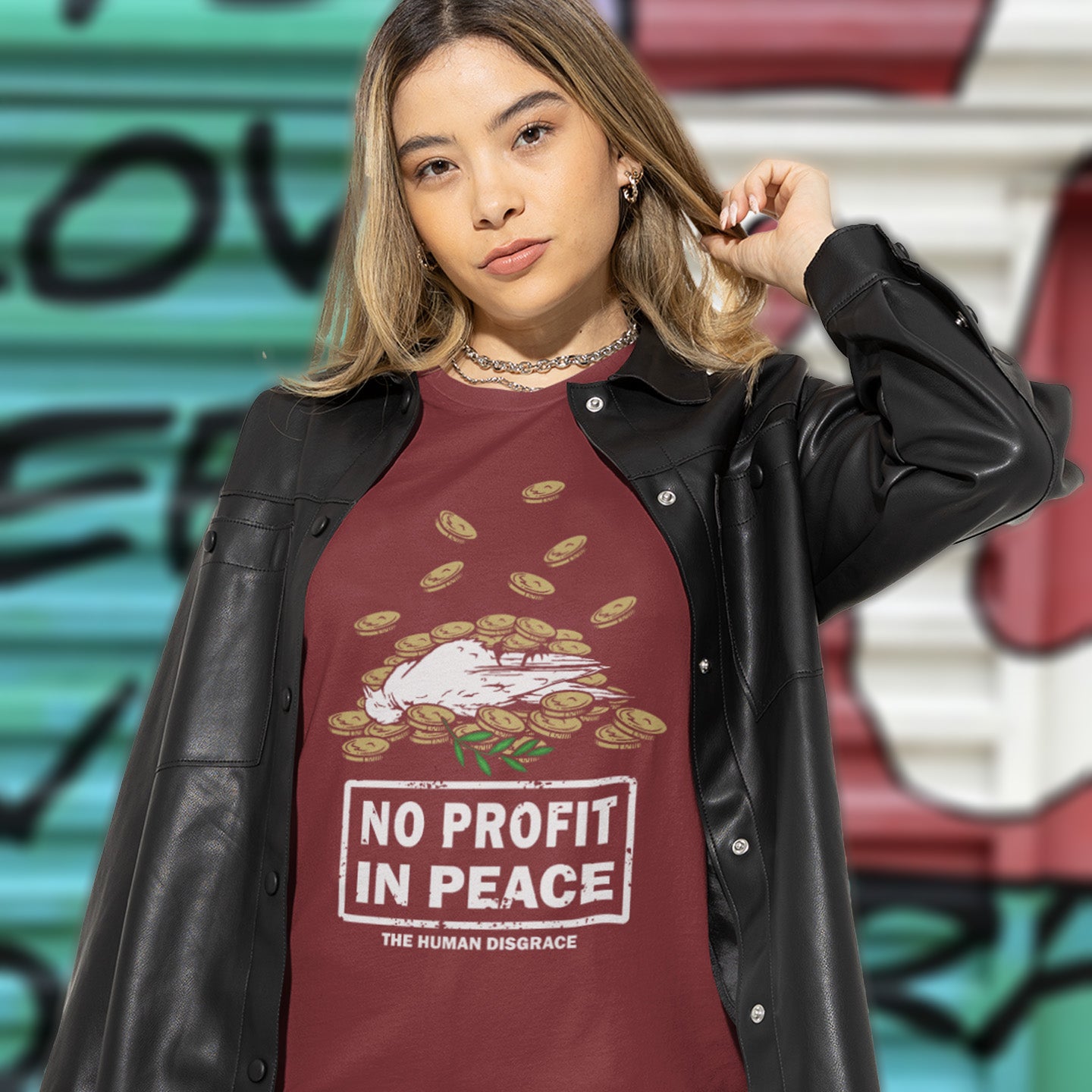 Person wearing a burgundy t-shirt with 'No Profit in Peace' design and black leather jacket against a graffiti-covered wall. An anti-war t-shirt exposing the true reason for war. A cynical view of why peace has never really been an option and what big business war has always been. Made from 100% organic ring-spun cotton, this political t-shirt is unisex, high-quality, super comfy, and best of all, eco-friendly.