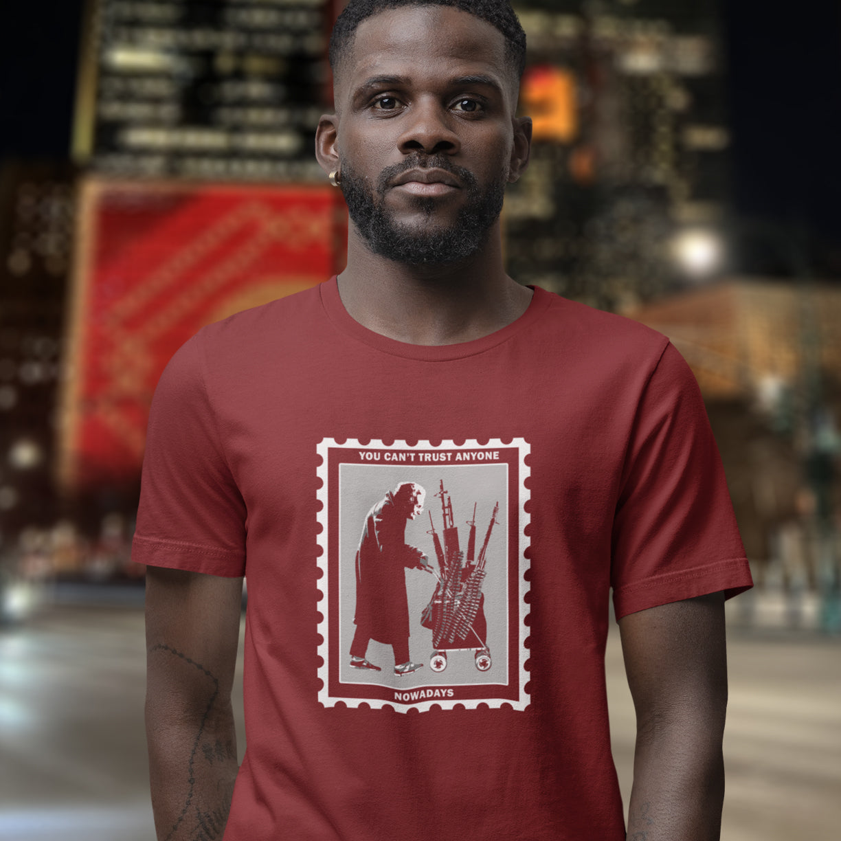 Man wearing a burgundy t-shirt with a graphic design and text. A stencil graffiti t shirt displaying a humorous view of how careful you have to be living in a culture of fear when you come from a more trusting generation. Made from 100% organic ring-spun cotton, this urban art t shirt is unisex, high-quality, super comfy, and best of all, eco-friendly.