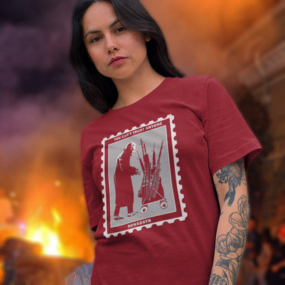 Woman wearing a burgundy t-shirt with a graphic design, standing against a blurred background. A Banksy style street art stencil t-shirt displaying a humorous view of how careful you have to be living in a culture of fear when you come from a more trusting generation. Made from 100% organic ring-spun cotton, this street art t-shirt is unisex, high-quality, super comfy, and best of all, eco-friendly.