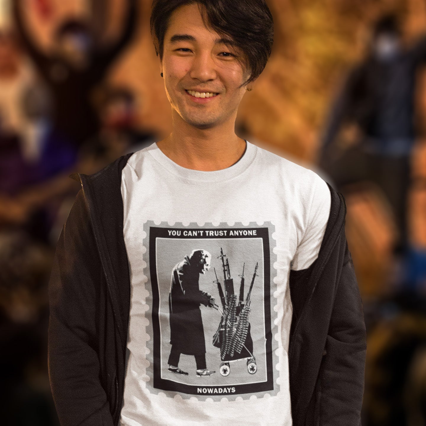 Person wearing a white t-shirt with a graphic design and text, standing in a blurred indoor setting. A Banksy style street art stencil t-shirt displaying a humorous view of how careful you have to be living in a culture of fear when you come from a more trusting generation. Made from 100% organic ring-spun cotton, this street art t-shirt is unisex, high-quality, super comfy, and best of all, eco-friendly.