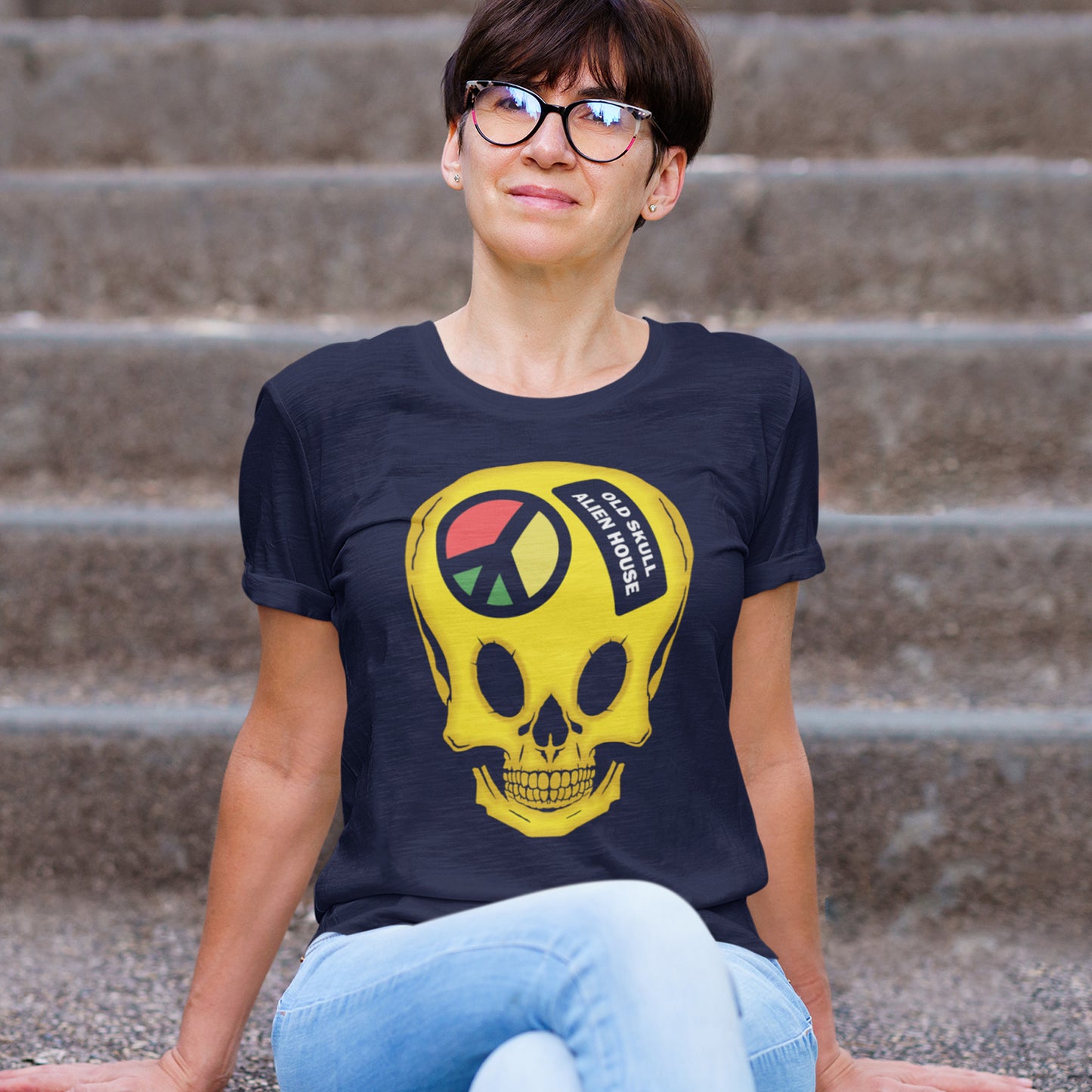 Person wearing a French navy t-shirt with a colourful skull design sitting on steps. A twisted 90's acid house t shirt design. You would be forgiven for having a fuzzy memory of the 90's if you were involved in the rave scene. An old skool acid house design for people who think outside the box and love aliens. Made from 100% organic ring-spun cotton, this funny 90's acid house t shirt is unisex, high-quality, super comfy, and best of all, eco-friendly.