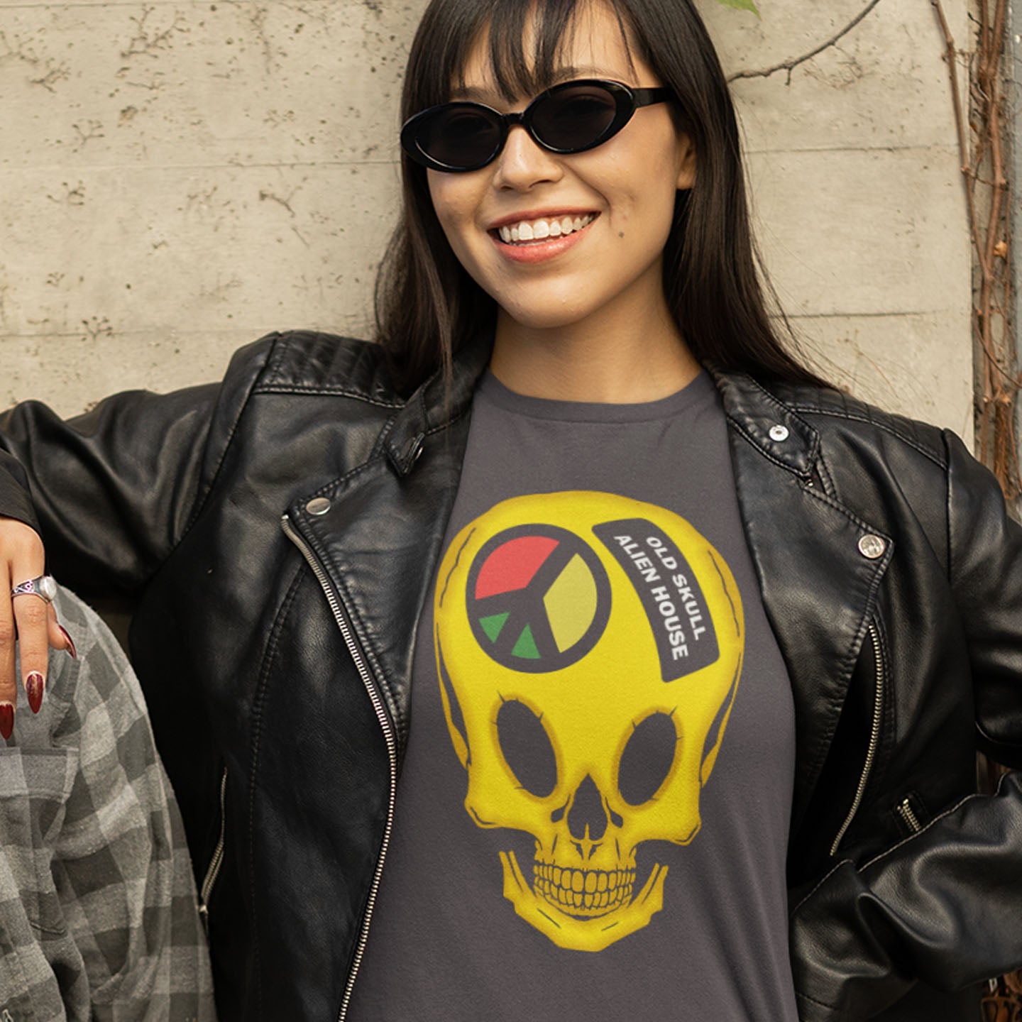 Woman wearing a black leather jacket and a t-shirt with a yellow skull design and text. A twisted 90's acid house t shirt design. You would be forgiven for having a fuzzy memory of the 90's if you were involved in the rave scene. An old skool acid house design for people who think outside the box and love aliens. Made from 100% organic ring-spun cotton, this funny 90's acid house t shirt is unisex, high-quality, super comfy, and best of all, eco-friendly.