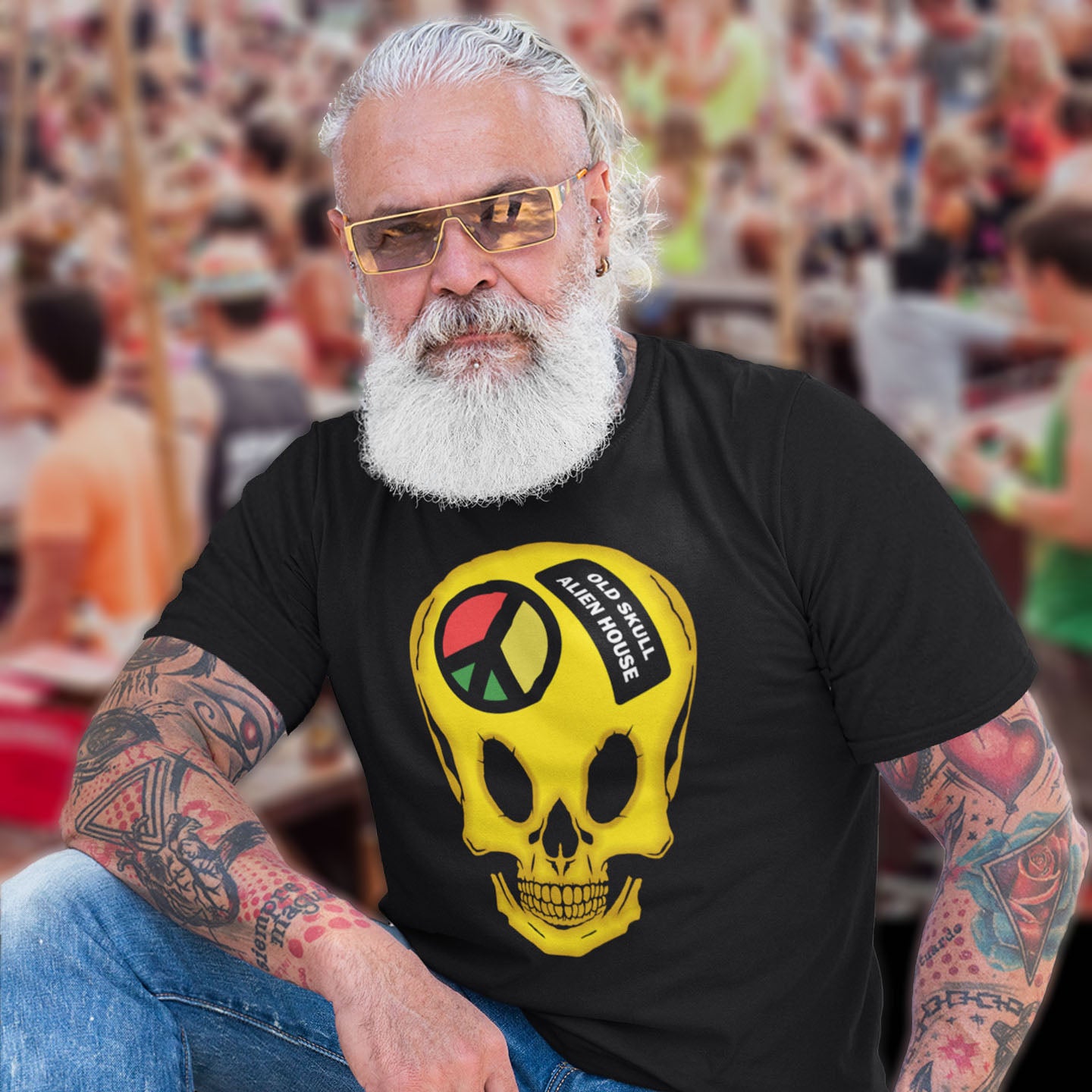 Man wearing a black t-shirt with a yellow skull design and text, sitting in a crowd. A twisted 90's acid house t shirt design. You would be forgiven for having a fuzzy memory of the 90's if you were involved in the rave scene. An old skool acid house design for people who think outside the box and love aliens. Made from 100% organic ring-spun cotton, this funny 90's acid house t shirt is unisex, high-quality, super comfy, and best of all, eco-friendly.