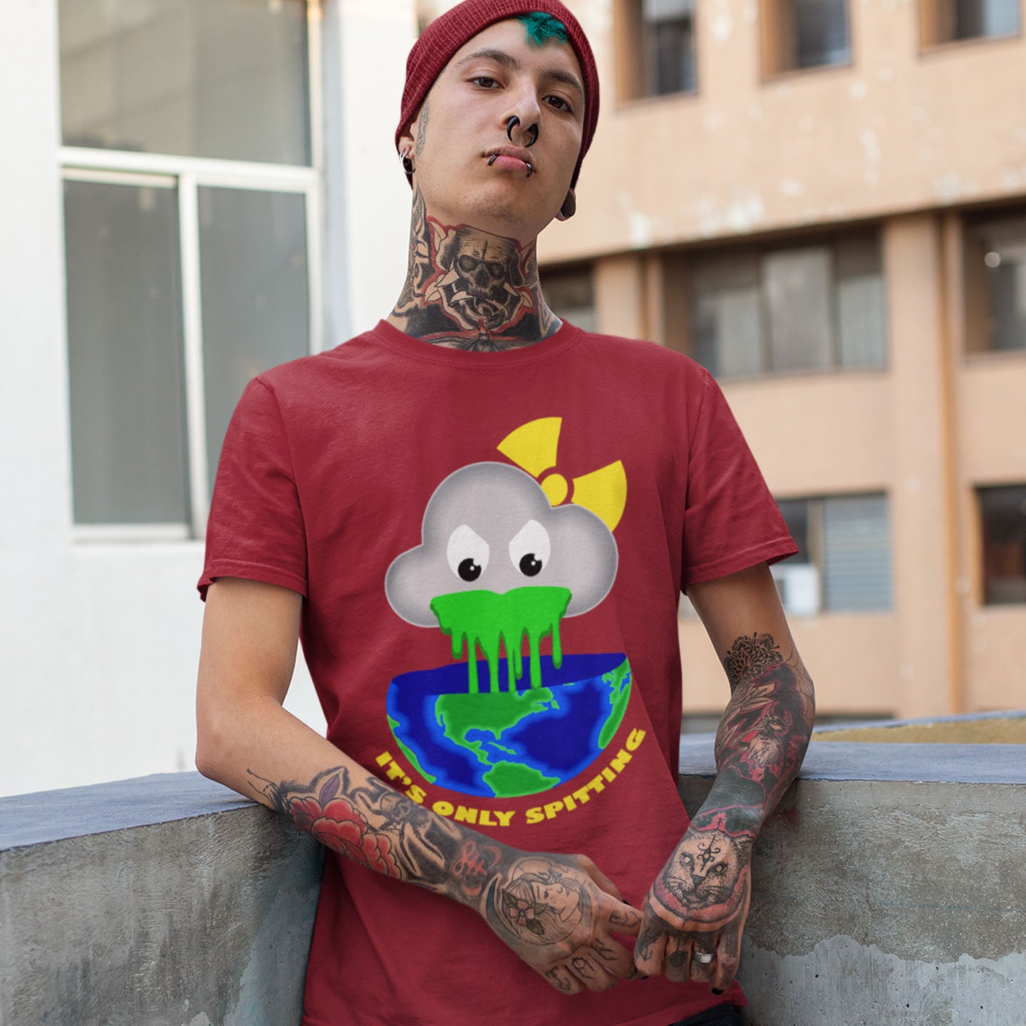 Person wearing a red t-shirt with a graphic design of a cloud spitting on the Earth, standing outdoors. A sarcastic climate awareness t-shirt. We can pretend we're not having a climate crisis but we'll pay for it later. This unique design is a dig at actionless optimism. Made from 100% organic ring-spun cotton, this environmental awareness t-shirt is unisex, high-quality, super comfy, and best of all, eco-friendly.