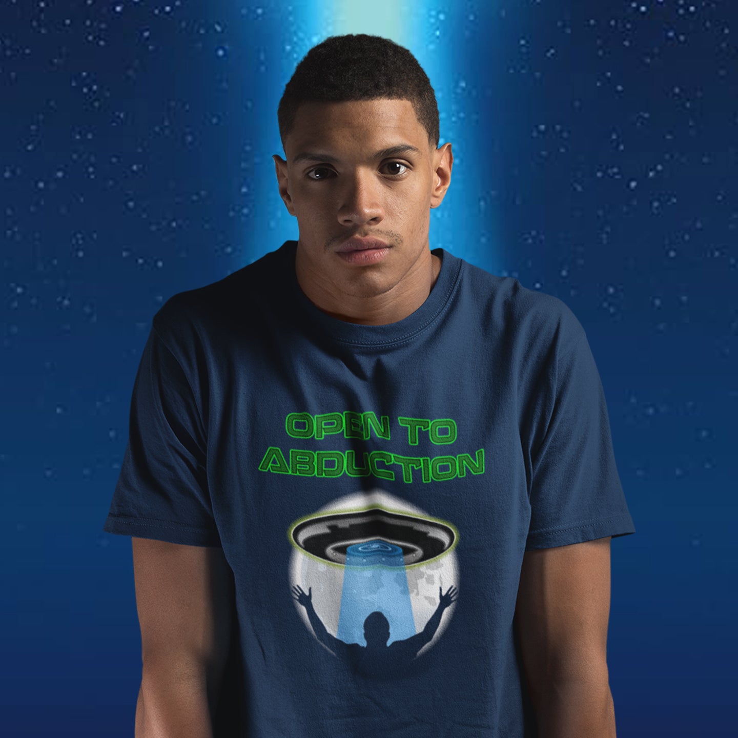 Person wearing a t-shirt with 'Open to Abduction' graphic design on a blue background. A funny alien abduction t-shirt design for those who feel a distance forming between them and the rest of the human race, and are not too impressed with our lack of effort to save the planet. This design depicts a man open to abduction. Made from 100% organic ring-spun cotton, this witty alien abduction t-shirt is unisex, high-quality, super comfy, and best of all, eco-friendly.
