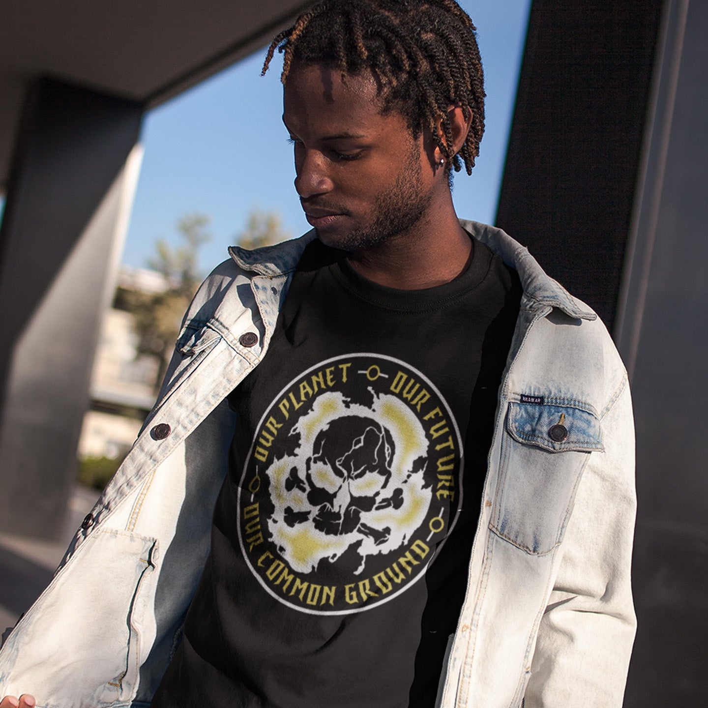 Person wearing a black t-shirt with a graphic design and text, standing outdoors. An environmental concern t-shirt for nature lovers who want to save the planet. Planet welfare should be something we can all agree on. Made from 100% organic ring-spun cotton, this climate concern t-shirt is unisex, high-quality, super comfy, and best of all, eco-friendly.