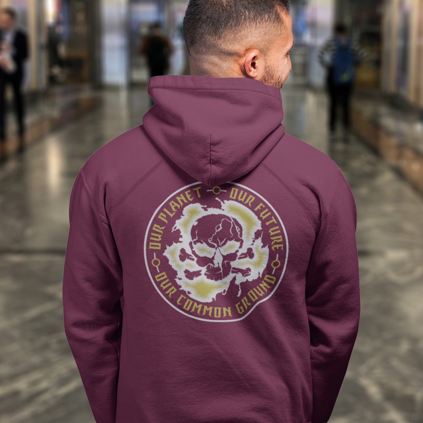 Person wearing a maroon hoodie with a skull design and text in an indoor setting. An environmental concern hoodie for nature lovers who want to save the planet. Planet welfare should be something we can all agree on. Comfortable and practical. It's extra soft and has a convenient front pouch pocket. Made from organic cotton and recycled polyester, this environmental awareness hoodie is a great eco-friendly choice.