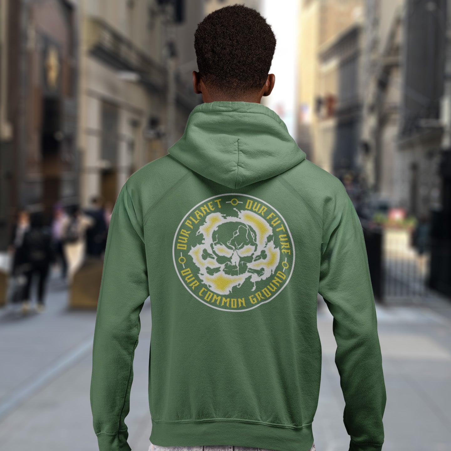 Person wearing a bottle green hoodie with a graphic design on the back, standing on a city street. A save the Earth hoodie in a grey design, for nature lovers who have environmental concern. Planet welfare should be something we can all agree on. Comfortable and practical. It's extra soft and has a convenient front pouch pocket. Made from organic cotton and recycled polyester, this save the world hoodie is a great eco-friendly choice.