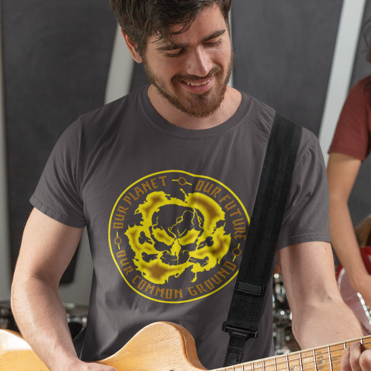 Man playing guitar wearing a t-shirt with a yellow graphic design. An environmental concern t-shirt for nature lovers who want to save the planet. Planet welfare should be something we can all agree on. Made from 100% organic ring-spun cotton, this climate concern t-shirt is unisex, high-quality, super comfy, and best of all, eco-friendly. yellow design.