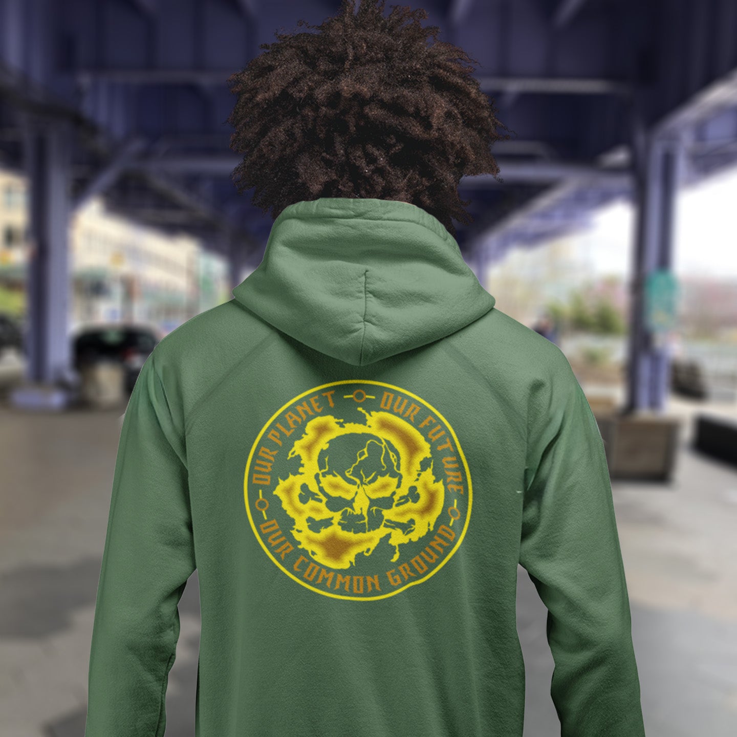 Person wearing a bottle green hoodie with a yellow graphic and text on the back, standing in an outdoor setting. A save the Earth hoodie in a yellow design, for nature lovers who have environmental concern. Planet welfare should be something we can all agree on. Comfortable and practical. It's extra soft and has a convenient front pouch pocket. Made from organic cotton and recycled polyester, this save the world hoodie is a great eco-friendly choice.