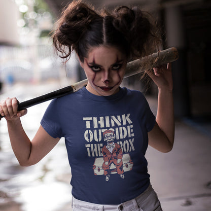 A woman with clown makeup and a baseball bat, wearing a French navy  t-shirt featuring a graphic print on the front. The graphic displays the text 'THINK OUTSIDE THE BOX' in a distressed beige font above an illustration of a ventriloquist dummy.