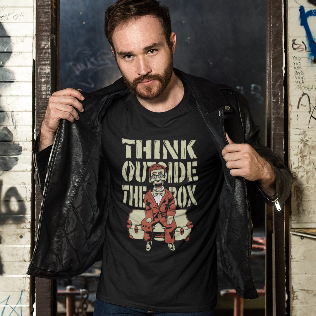 Man wearing a black t shirt with 'think outside the box' text. A think outside the box t shirt to promote diversity of thought. Trust the ventriloquist dummy to know thinking outside the box is liberating and progressive. Promote independent and creative thinking with this unique urban art design. Made from 100% organic ring-spun cotton, this counter culture t shirt is unisex, high quality, super comfy, and best of all, eco-friendly.