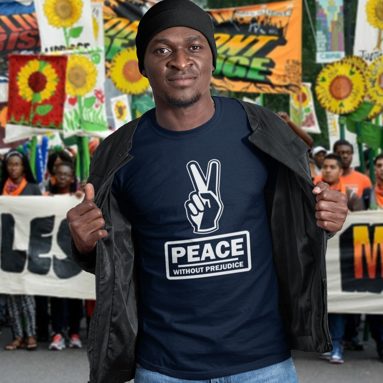 Man wearing a 'Peace Without Prejudice' t-shirt at a protest rally with colorful banners in the background. This anti racism t-shirt highlights how equality is a key component of peace on Earth. For us to live in harmony we need to improve our emotional intelligence and acceptance of differences, especially when it comes to racial issues. Made from 100% organic ring-spun cotton, this anti racist t shirt is unisex, high-quality, super comfy, and best of all, eco-friendly.