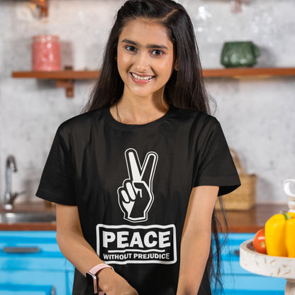 Person wearing a black t-shirt with a peace symbol and 'Peace Without Prejudice' text in a kitchen setting. This anti racism t-shirt highlights how equality is a key component of peace on Earth. For us to live in harmony we need to improve our emotional intelligence and acceptance of differences, especially when it comes to racial issues. Made from 100% organic ring-spun cotton, this anti racist t shirt is unisex, high-quality, super comfy, and best of all, eco-friendly.
