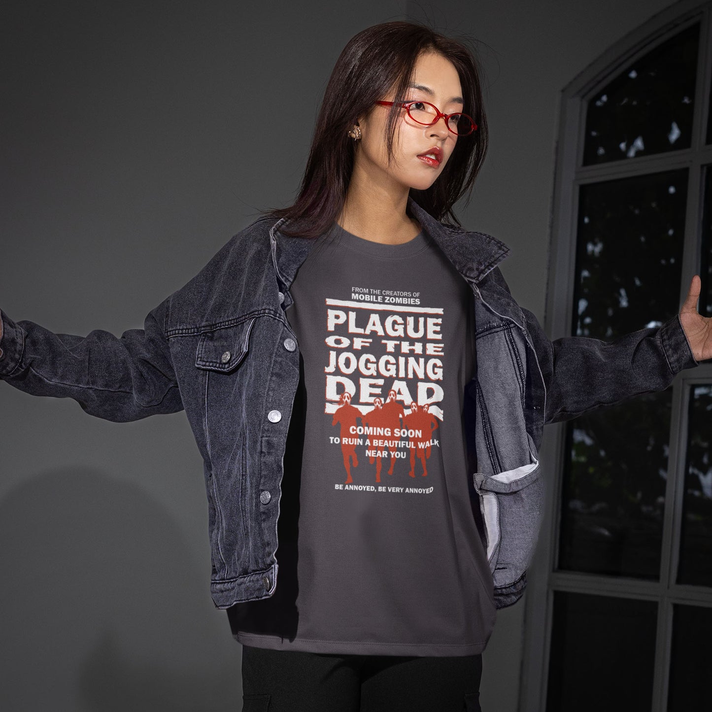 Person wearing a dark denim jacket and graphic t-shirt with text and images. A satirical t-shirt about jogging in a horror movie design. Just when you thought it was safe to go out for a nice relaxing walk. Made from 100% organic ring-spun cotton, this social awareness t-shirt is unisex, high-quality, super comfy, and best of all, eco-friendly.