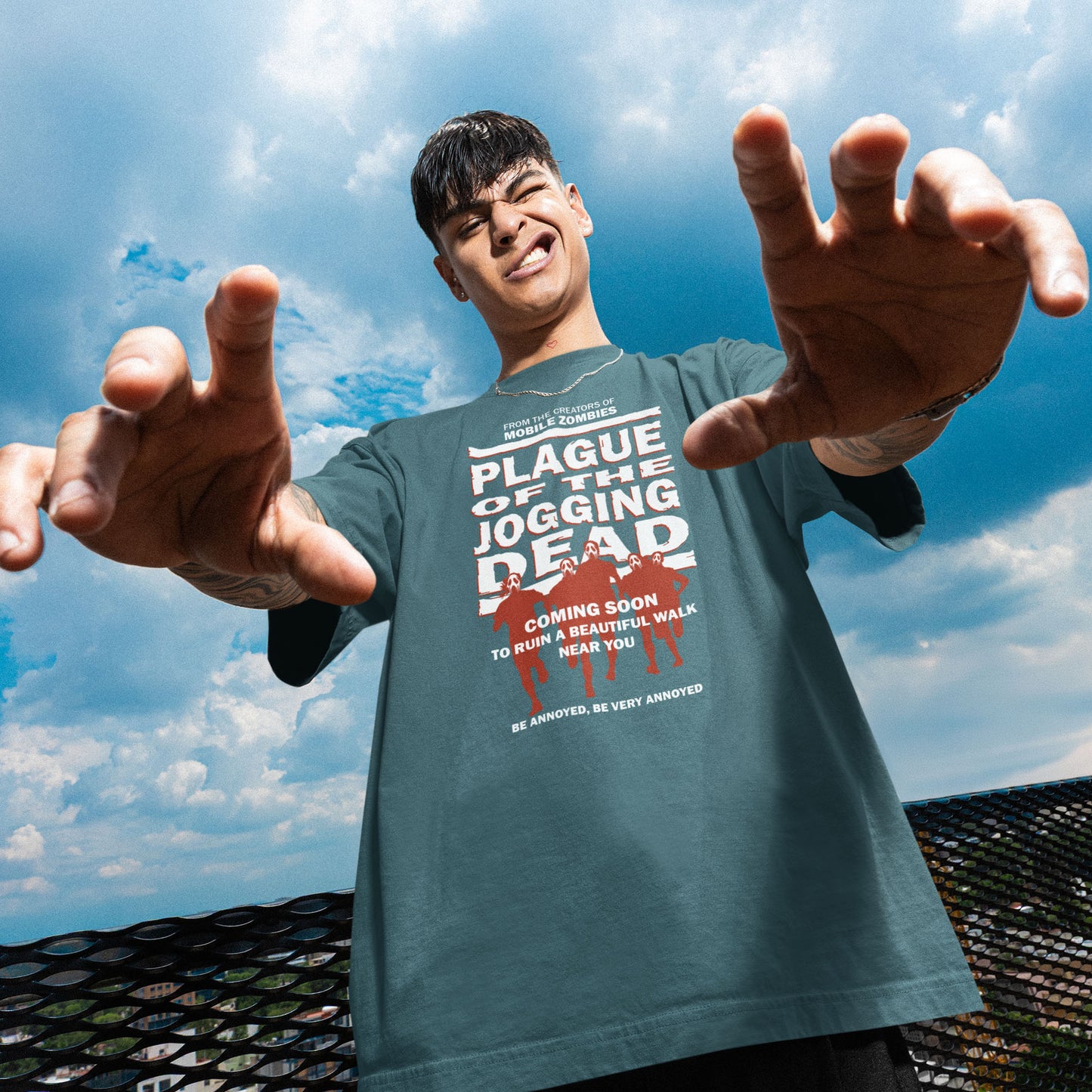 Person wearing a t-shirt with a humorous graphic and text against a blue sky. A satirical t-shirt about jogging in a horror movie design. Just when you thought it was safe to go out for a nice relaxing walk. Made from 100% organic ring-spun cotton, this social awareness t-shirt is unisex, high-quality, super comfy, and best of all, eco-friendly.