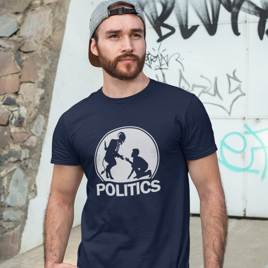 A man standing in front of a graffiti wall, wearing a French navy T-shirt with a white graphic print on the chest. The graphic features a circular silhouette illustration of a standing figure reaching toward a kneeling figure, with the word 'POLITICS' printed in bold white capital letters underneath.
