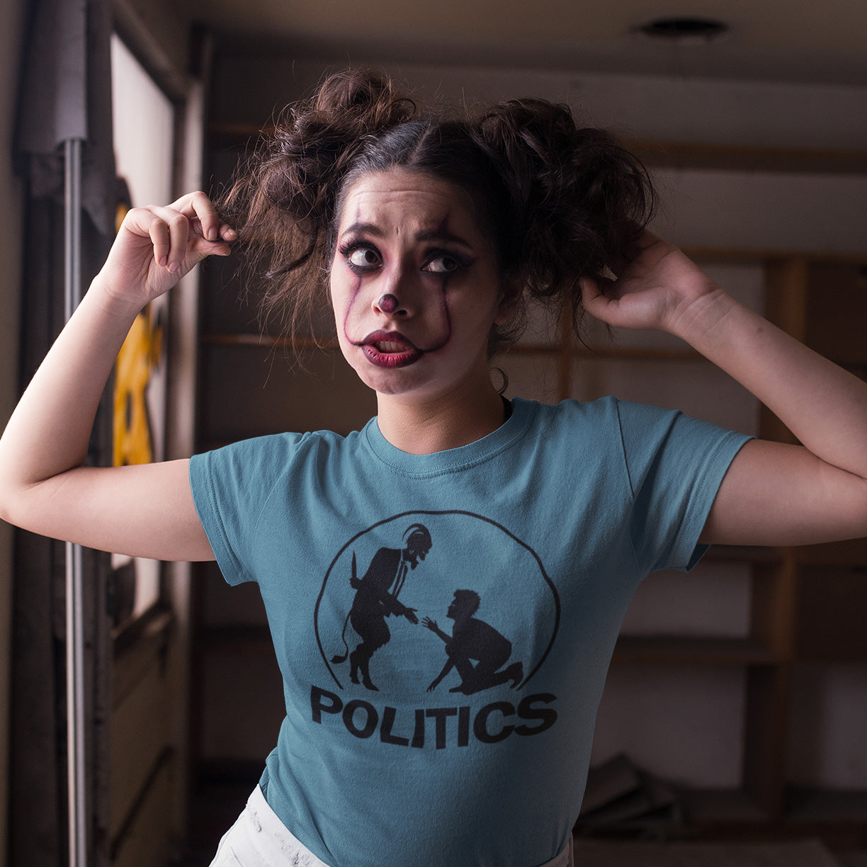Person wearing a blue t-shirt with a graphic and the word 'POLITICS' in a room. An anti government t shirt representing the simple inner workings of politics. Are they not stabbing the working class in the back to help the rich get richer ? Show your disapproval with this urban art t shirt. Made from 100% organic ring-spun cotton, this funny political t shirt is unisex, high-quality, super comfy, and best of all, eco-friendly.