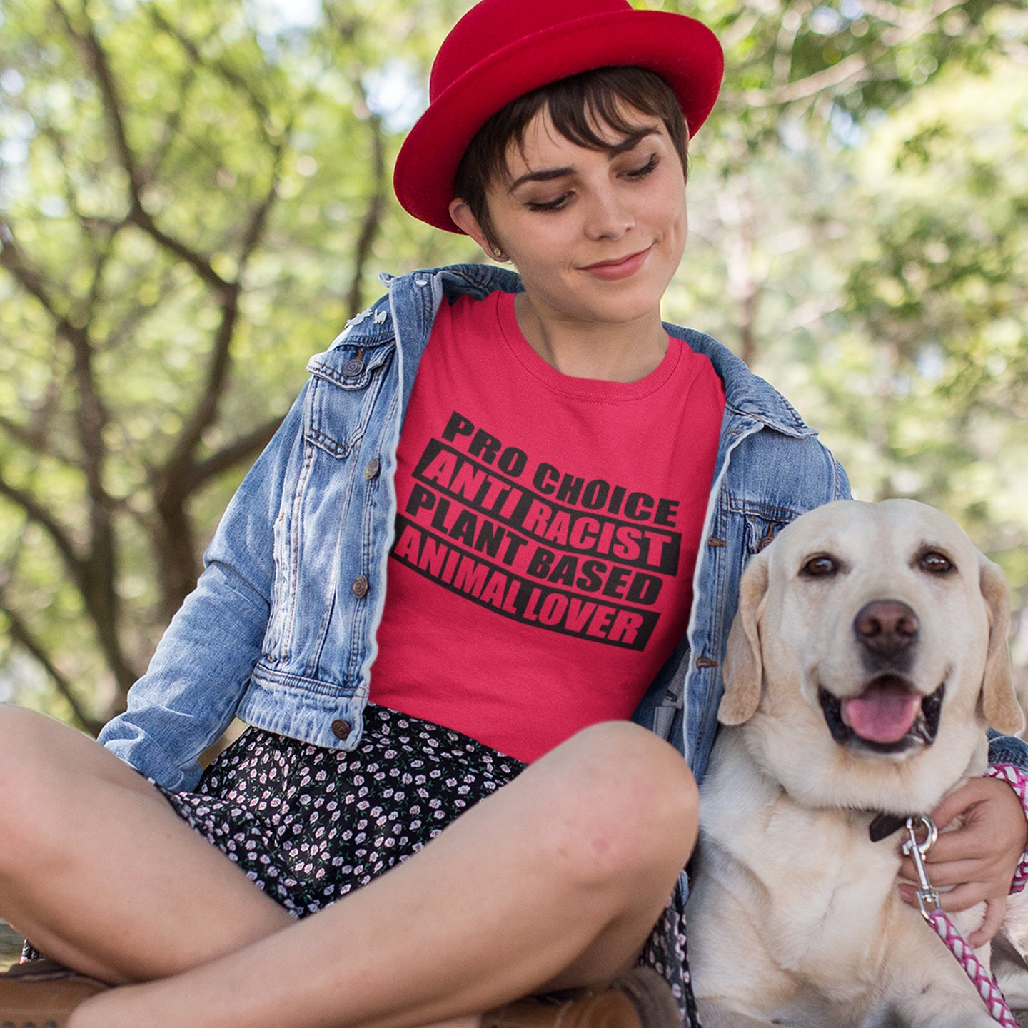 Person wearing a red shirt with text, sitting outdoors with a dog. A plant based t-shirt design intertwined with Pro Choice, Anti Racism, and Animal loving, characteristics that often go together. Made from 100% organic ring-spun cotton, this vegan t-shirt is unisex, high-quality, super comfy, and best of all, eco-friendly.