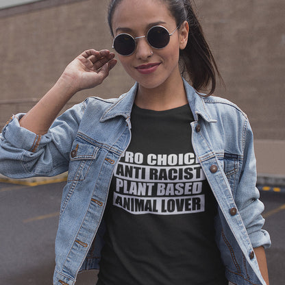 Person wearing a denim jacket and black t-shirt with text, standing outdoors. A plant based meat free t shirt design intertwined with Pro Choice, Anti Racism, and Animal loving, characteristics that often go together. Made from 100% organic ring-spun cotton, this dairy free t shirt is unisex, high-quality, super comfy, and best of all, eco-friendly.