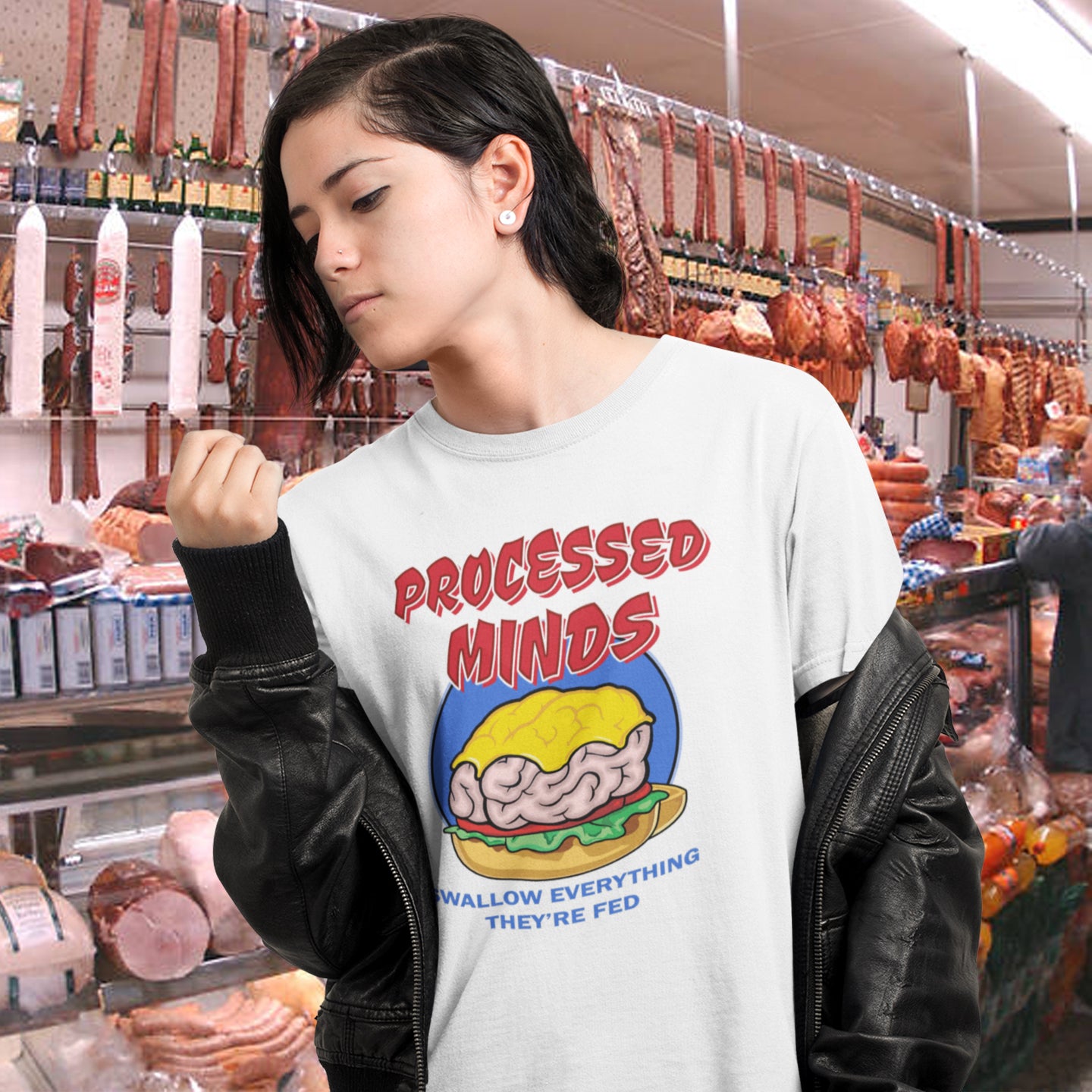 Woman in butcher shop wearing white 'processed minds t-shirt. This counterculture design represents the amount of influence and mental manipulation in circulation these days. Resist the brainwashing and bring back wild and organic independent thinking. Made from 100% organic ring-spun cotton, this social awareness t-shirt is unisex, high-quality, super comfy, and best of all, eco-friendly.