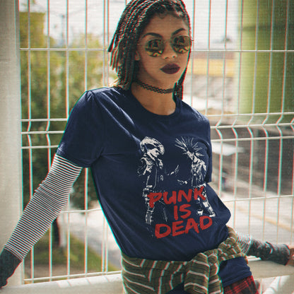 Person wearing a French navy blue t-shirt with 'Punk is Dead' graphic design, sitting on a ledge. A funny punk t shirt suggesting that the mobile phone is a symbol of conformity. This controversial design questions the slogan, 'Punks not dead' by suggesting that reliance on the mobile phone is very unpunk. Made from 100% organic ring-spun cotton, this urban art t shirt is unisex, high-quality, super comfy, and best of all, eco-friendly.