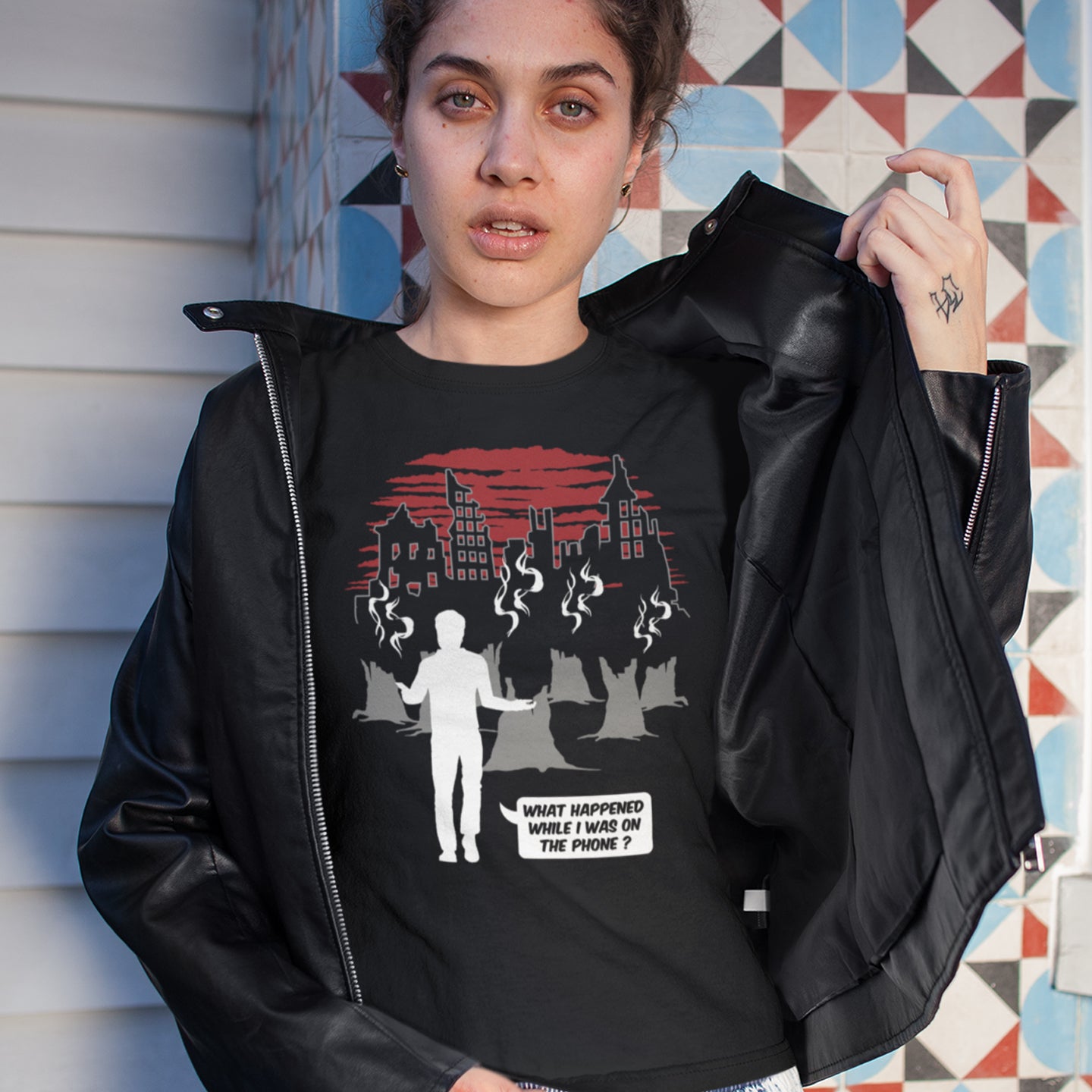 Person wearing a black t-shirt with graphic design and text, standing against a colourful geometric-patterned wall. This environmental concern t-shirt asks the question Is the mobile phone the ultimate distraction from the real issues going on in the World. Let's put down the phone and save the planet. Climate concern is not an app. Made from 100% organic ring-spun cotton, this social awareness &amp; environmental concern t-shirt is unisex, high-quality, super comfy, and best of all, eco-friendly.