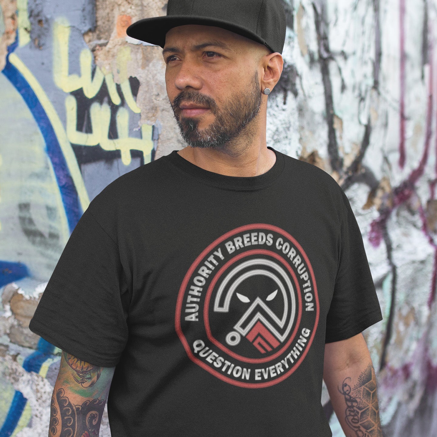 Man wearing a black t-shirt in front of a graffiti-covered wall. A question everything t shirt for everyday defiance or leading the next protest rally. Help create social awareness of the dark side of human nature, how power corrupts and authority is abused. To be worn with pride in support of a world where authority should be answerable to the people who put them there. Made from 100% organic ring-spun cotton, this broken society t shirt is unisex, high quality, super comfy, and best of all, eco-friendly.