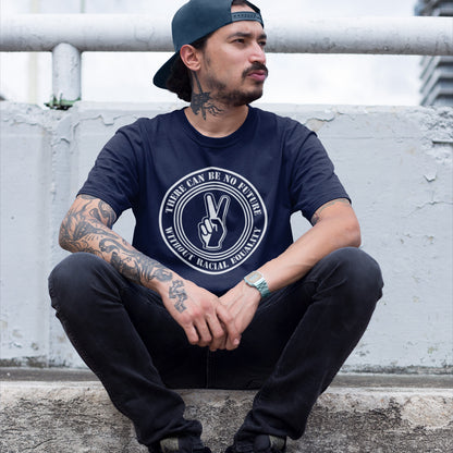 Man wearing a French navy blue t-shirt with a graphic design, sitting on a concrete surface. An anti-racism t-shirt denouncing prejudice. Peace without prejudice. There can be no future without racial equality. Made from 100% organic ring-spun cotton, this social awareness anti racism t-shirt is unisex, high-quality, super comfy, and best of all, eco-friendly.