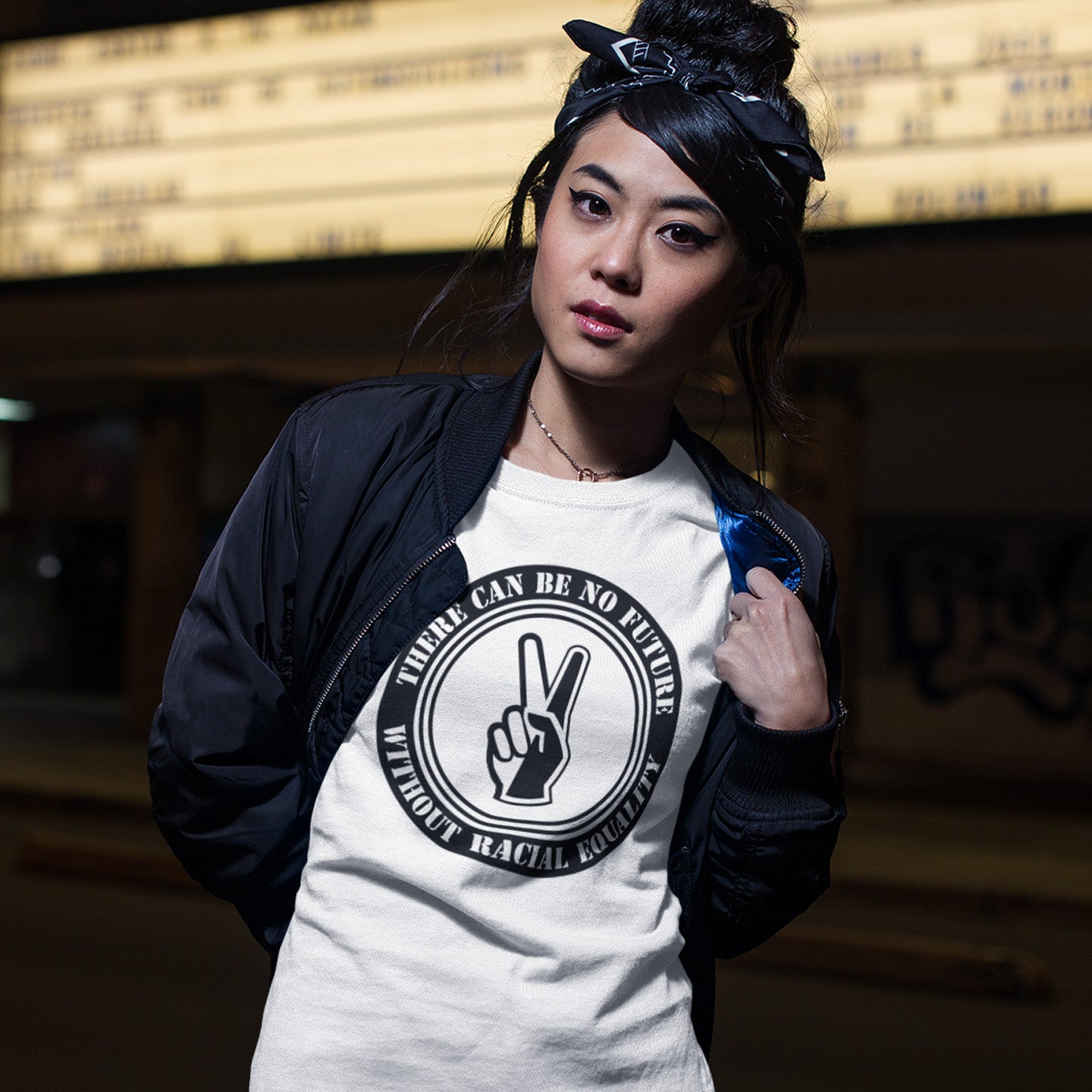 Person wearing a white t-shirt with a black graphic and text, standing against a dark background. An anti-racism t-shirt denouncing prejudice. Peace without prejudice. There can be no future without racial equality. Made from 100% organic ring-spun cotton, this social awareness anti racism t-shirt is unisex, high-quality, super comfy, and best of all, eco-friendly.