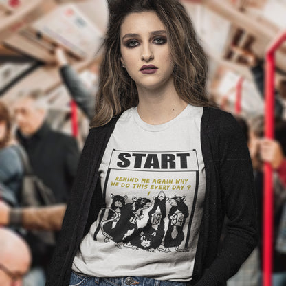 Woman wearing a t-shirt with a graphic design and text, standing in a train. This Banksy style stencil art t-shirt represents the monotony of everyday working life. A unique satirical design for those times when life starts to feel a little repetitive, unnecessary, and questionable. Made from 100% organic ring-spun cotton, this street art graffiti t-shirt is unisex, high-quality, super comfy, and best of all, eco-friendly.