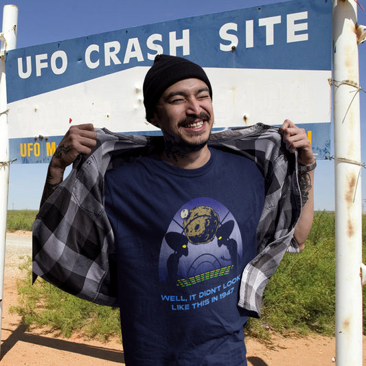 Person wearing a shirt with a UFO design in front of a 'UFO Crash Site' sign. A funny alien t shirt for lovers of conspiracy theory. Imagine the aliens from the 1947 Roswell incident coming back in the future to see what we've done with the place. Made from 100% organic ring-spun cotton, this funny alien t shirt is unisex, high-quality, super comfy, and best of all, eco-friendly.