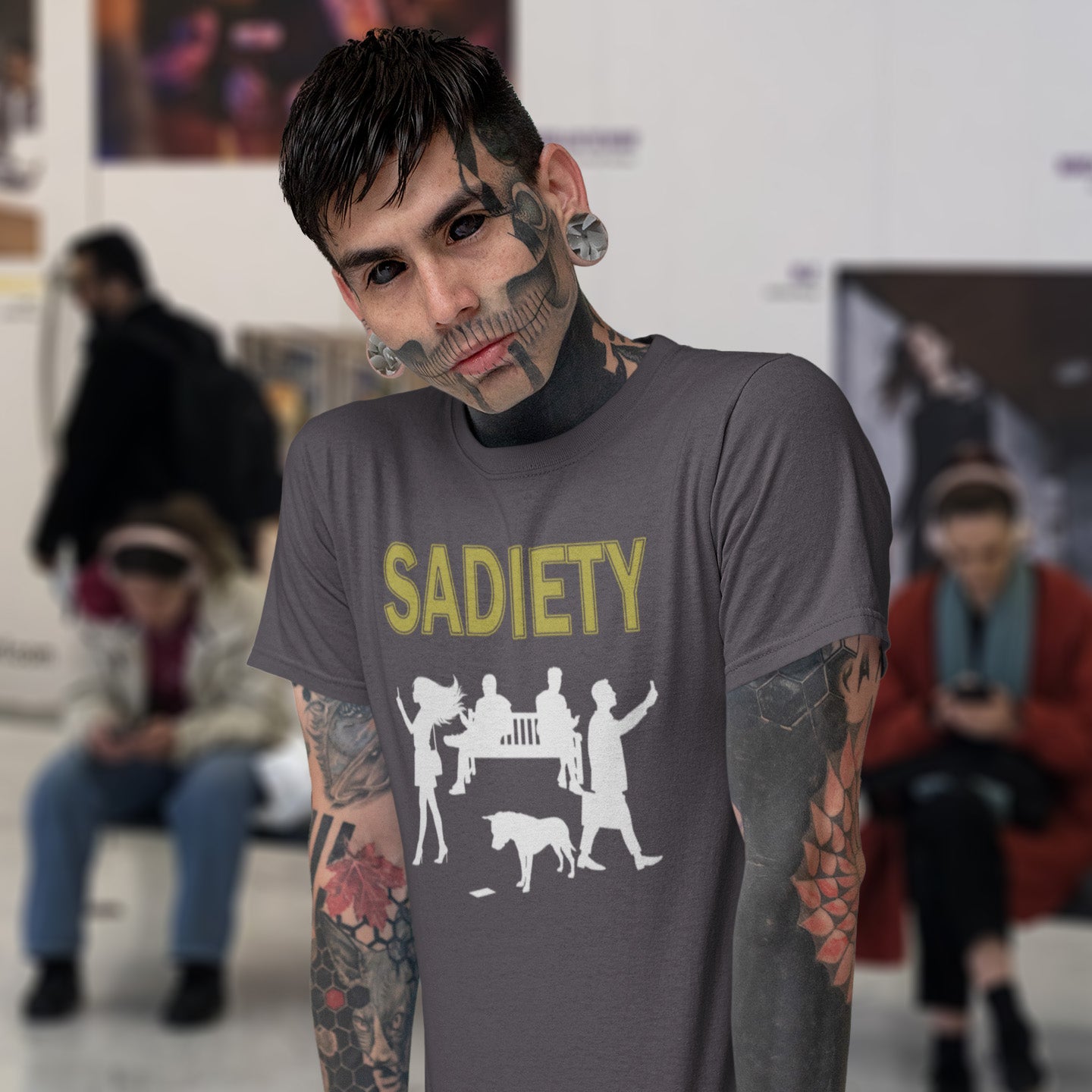 Person wearing an anthracite t-shirt with 'SADIETY' design in a public setting. An anti mobile phone abuse t shirt design promoting social awareness about the effects of the mobile phone on society and sociability. The mobile phone has made people in close proximity seem miles apart. It's not a society, it's sadiety. Made from 100% organic ring-spun cotton, this stencil graffiti t shirt is unisex, high-quality, super comfy, and best of all, eco-friendly.