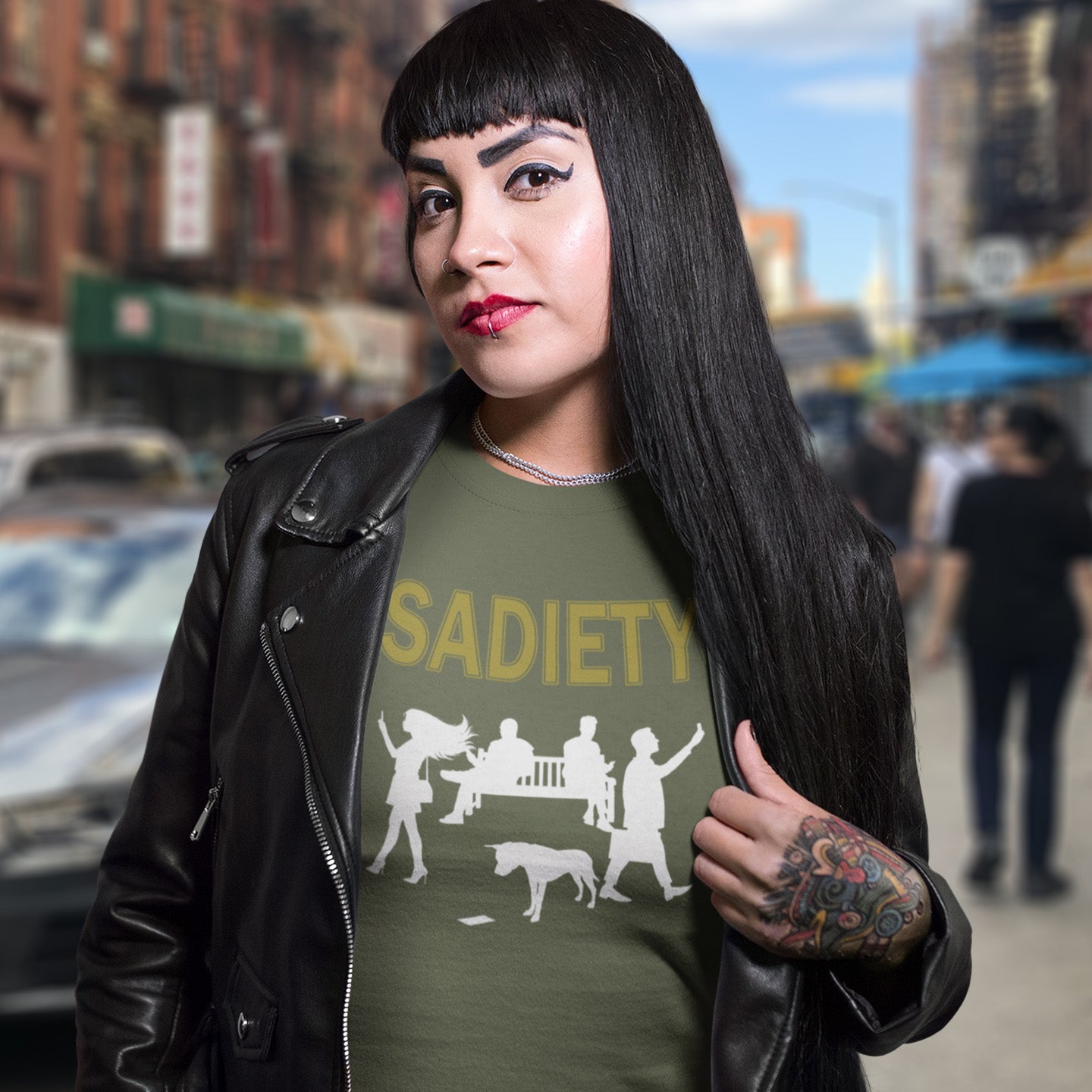 Woman wearing a khaki t-shirt with 'SADIETY' design in an urban setting. An anti mobile phone abuse t shirt design promoting social awareness about the effects of the mobile phone on society and sociability. The mobile phone has made people in close proximity seem miles apart. It's not a society, it's sadiety. Made from 100% organic ring-spun cotton, this stencil graffiti t shirt is unisex, high-quality, super comfy, and best of all, eco-friendly.