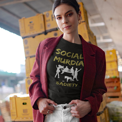 A woman wearing a black graphic t-shirt with a graphic print on the front. The print features the words 'SOCIAL MURDIA' in a textured gold font, a white silhouette of a group of people on smartphones and a dog, and the word 'SADIETY' in the same gold font below.