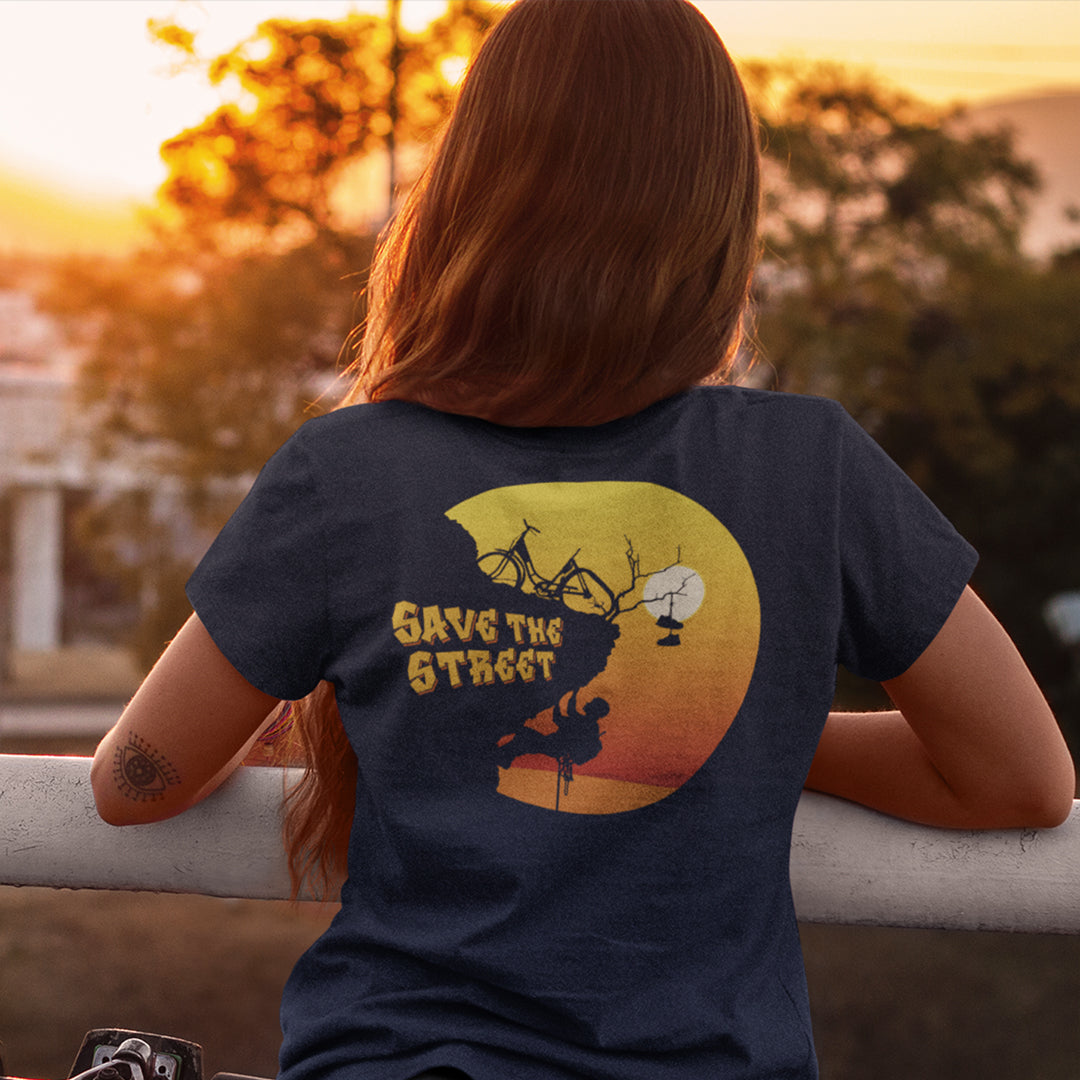 Person wearing a t-shirt with a graphic design and text, sitting on a ledge with a sunset background. A street art t shirt design paying homage to street life. As our society increasingly turns to an online based community it's worth giving a shout out to where the real community is based, on the streets! Let's keep them full of life. Made from 100% organic ring-spun cotton, these street art t shirts are unisex, high quality, super comfy, and best of all, eco-friendly.