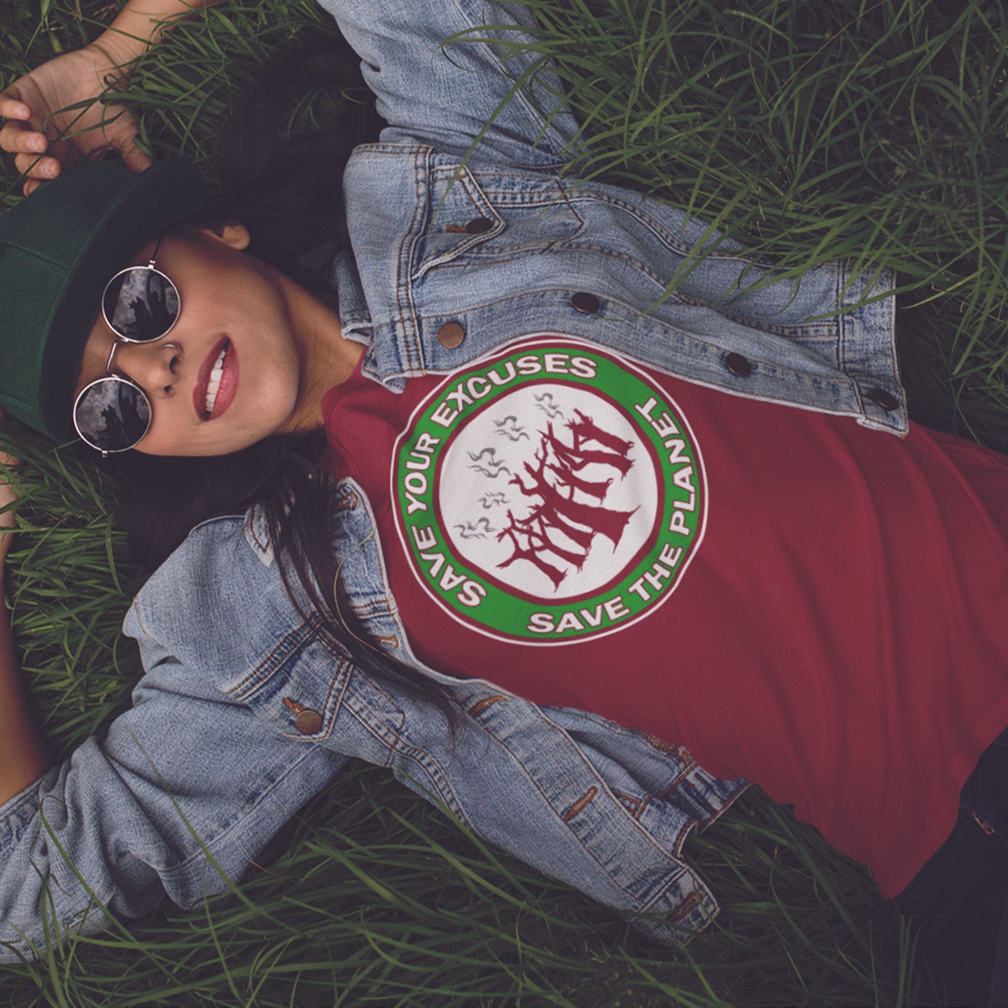 Person wearing a burgundy shirt with a graphic design lying on grass. A 'save the planet' t-shirt that promotes social awareness of environmental issues. It's time to stop making poor excuses for why our governments haven't got around to saving our planet yet. Made from 100% organic ring-spun cotton, this environmental awareness t-shirt is unisex, high-quality, super comfy, and best of all, eco-friendly.