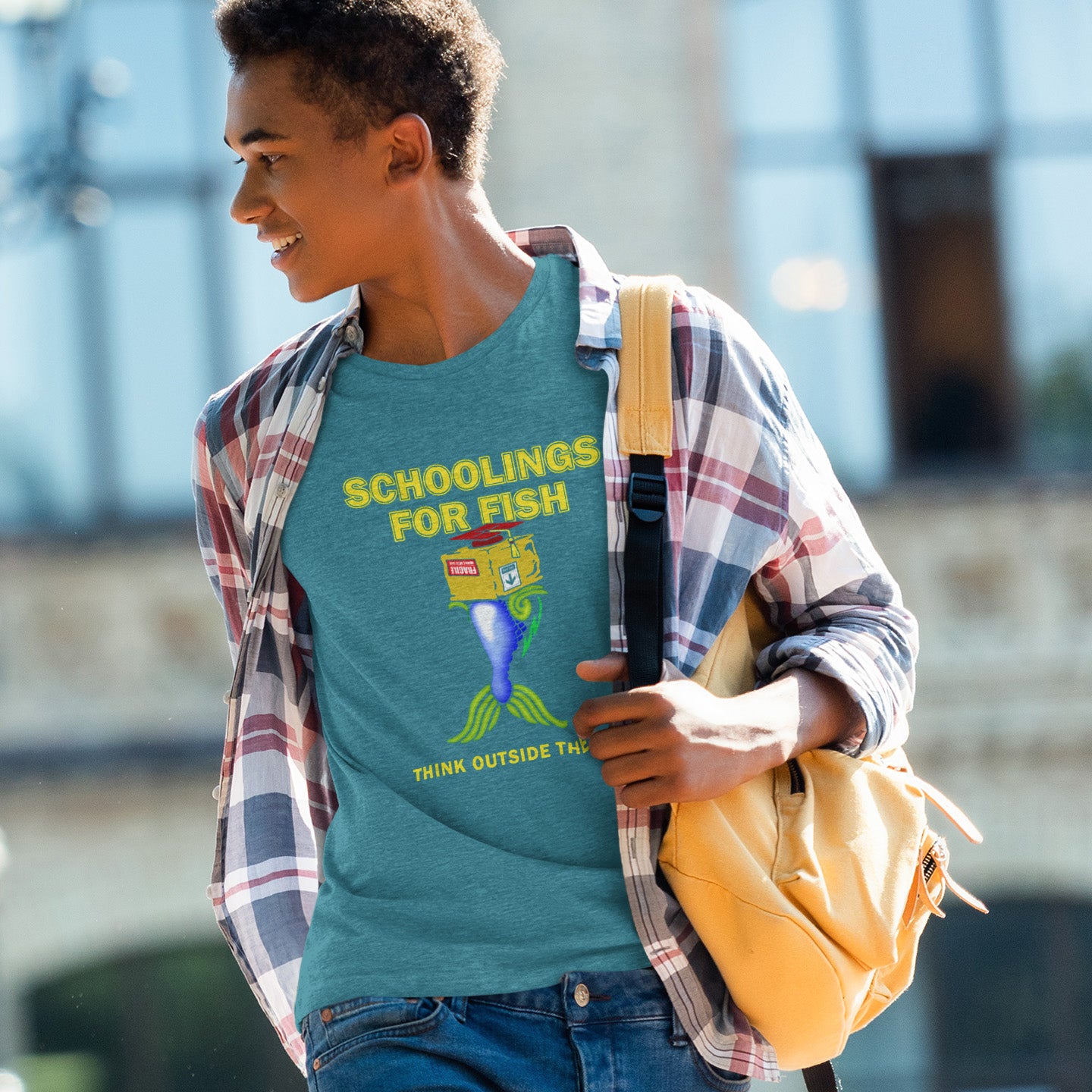 Person wearing a stargazer t-shirt with 'Schoolings for Fish' design, holding a yellow backpack. This alternative educational t-shirt design conveys a feeling that we are not quite being taught the full picture by our educational system. Great choice for any disgruntled student. Made from 100% organic ring-spun cotton, this witty counterculture t-shirt is unisex, high-quality, super comfy, and best of all, eco-friendly.
