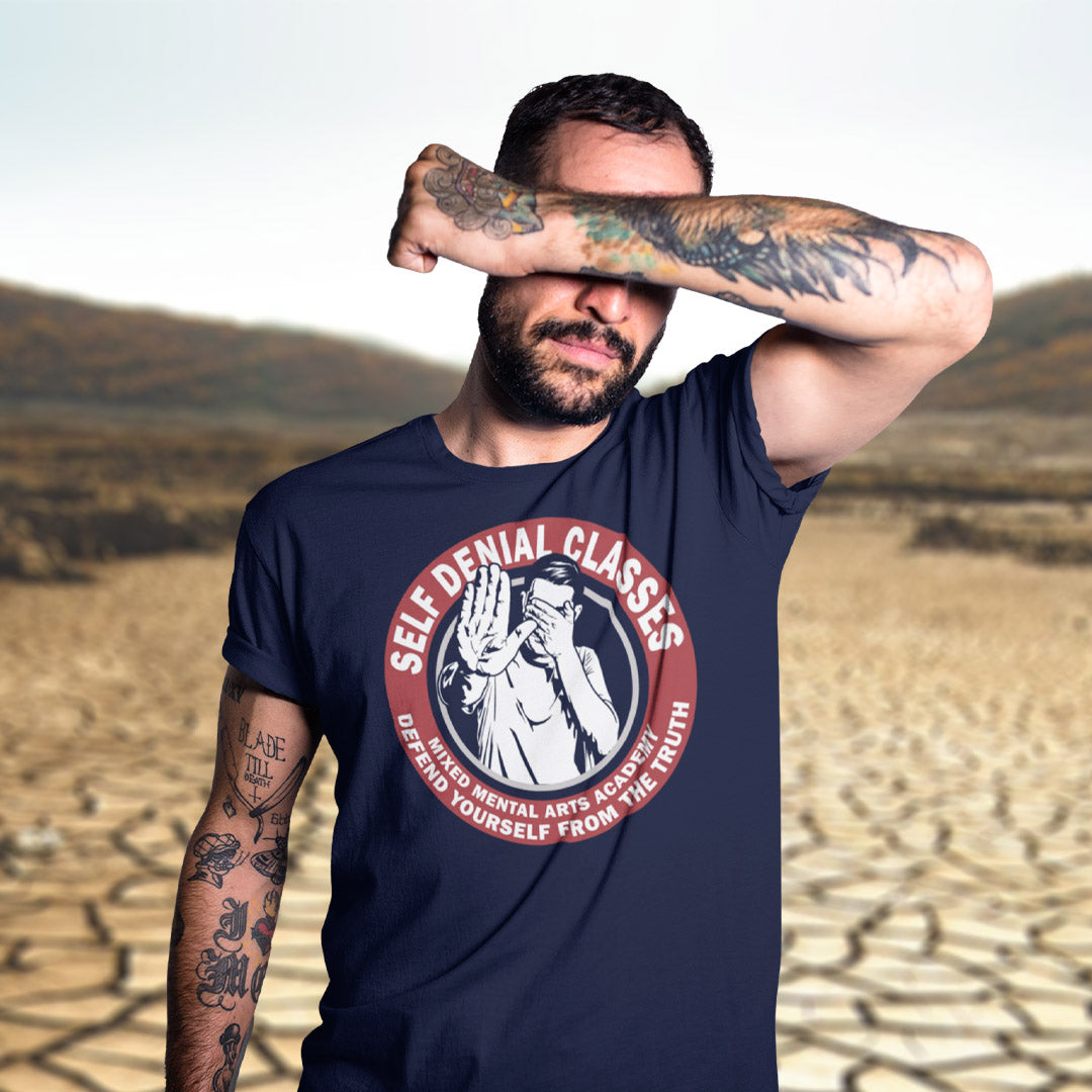 Man wearing a navy blue t-shirt with a graphic design in a desert setting. This emotional intelligence t shirt satirically highlights self denial as an increasing part of everyday life and suggests we could provide classes to improve it. This sarcastic urban art design laughs at people who want to protect themselves from the truth. Made from 100% organic ring-spun cotton, this broken society t shirt is unisex, high-quality, super comfy, and best of all, eco-friendly.