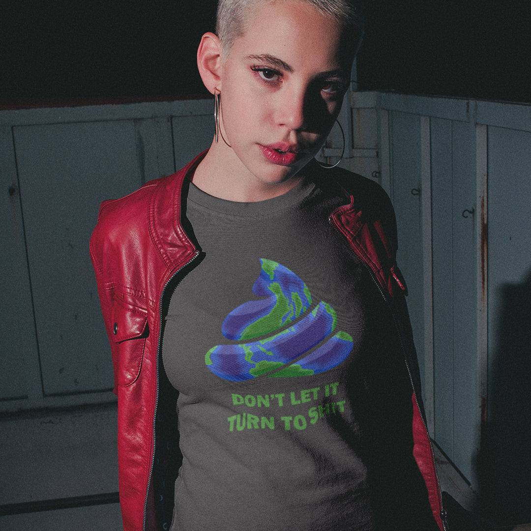 A short haired woman in a red jacket, wearing an anthracite grey t-shirt featuring a graphic of a swirling poop emoji with a blue and green globe pattern, above the text 'DON'T LET IT TURN TO SHIT' in green.