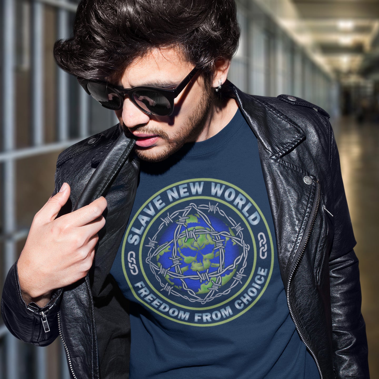 Man wearing a black leather jacket and sunglasses, with a blue t-shirt featuring text and graphics. A satirical wordplay on Aldous Huxley's novel Brave New World, this dystopian political t-shirt draws social awareness to our ever decreasing freedom of choice Made from 100% organic ring-spun cotton, this freedom fighters t-shirt is unisex, high-quality, super comfy, and best of all, eco-friendly.