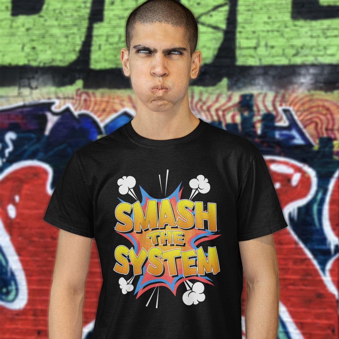 A man wearing a black graphic t-shirt with a colorful comic-style 'SMASH THE SYSTEM' design, standing in front of a graffiti-covered wall.