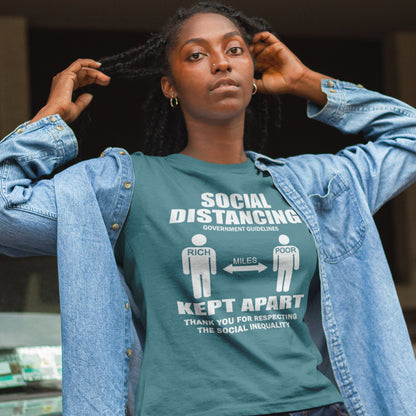 Person wearing a stargazer t-shirt with social distancing message, standing indoors. A class war t-shirt design representing a much older form of social distancing in our society. Class inequality. This anti-establishment t-shirt design promote social awareness of the class divide our system creates. Made from 100% organic ring-spun cotton, this nonconformist t-shirt is unisex, high-quality, super comfy, and best of all, eco-friendly.