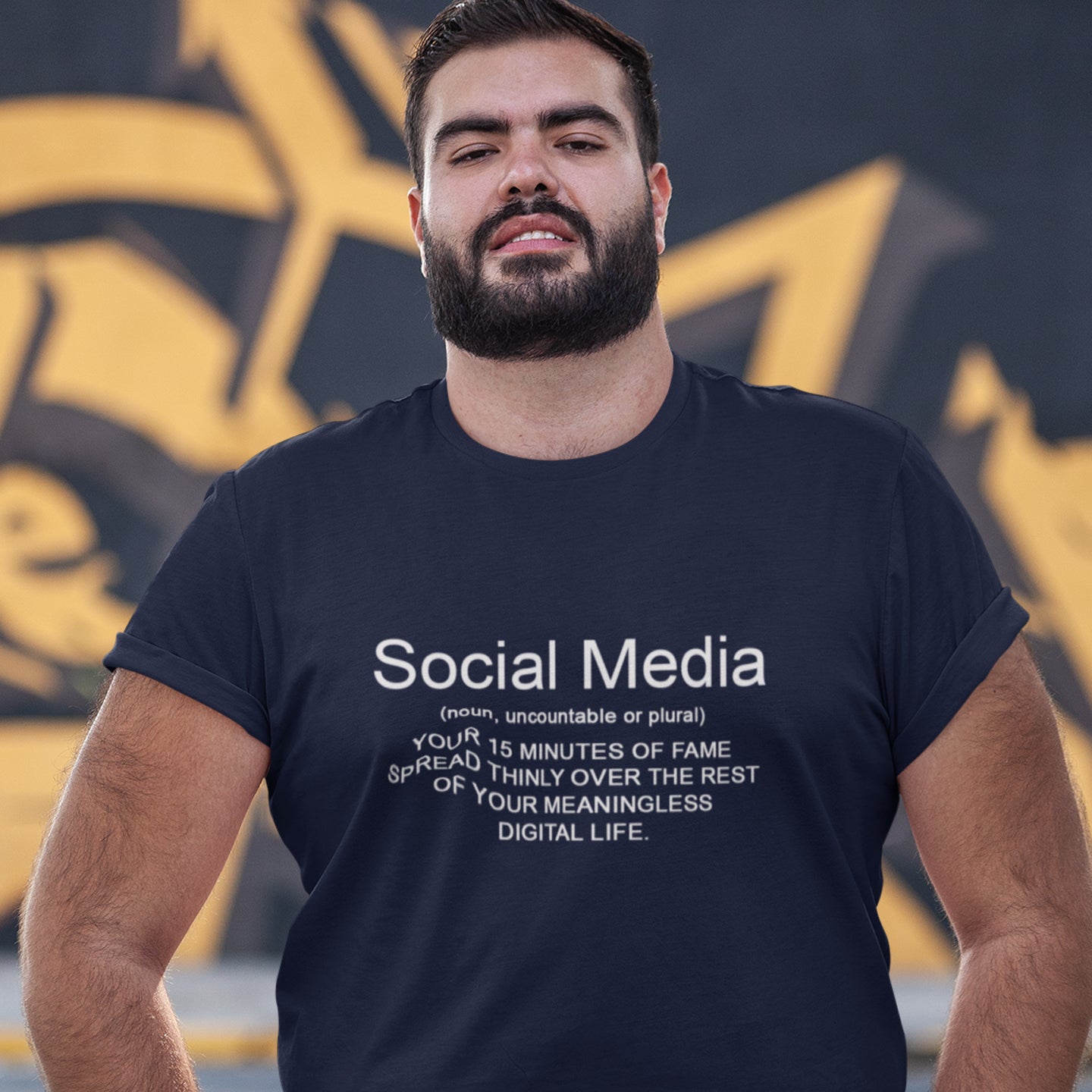 Man wearing a French navy blue t-shirt with a humorous social media definition, standing against a dark background. An anti-social media t-shirt with a humorous definition. A unique t-shirt design for those who still have a real life and consider 'community' to be something you can touch and walk around. Made from 100% organic ring-spun cotton, this anti social media t-shirt is unisex, high-quality, super comfy, and best of all, eco-friendly.